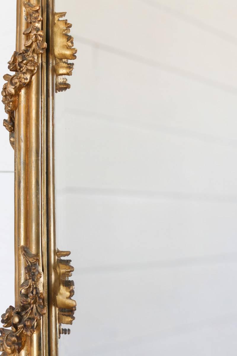 Elegant antique mirror with a large, elaborate floral crest. A winding vine travels its way around the frame lending an unusual, three dimensional effect to this stunning piece. Found near the commune of Aubagne in France, a bit of chipping on the