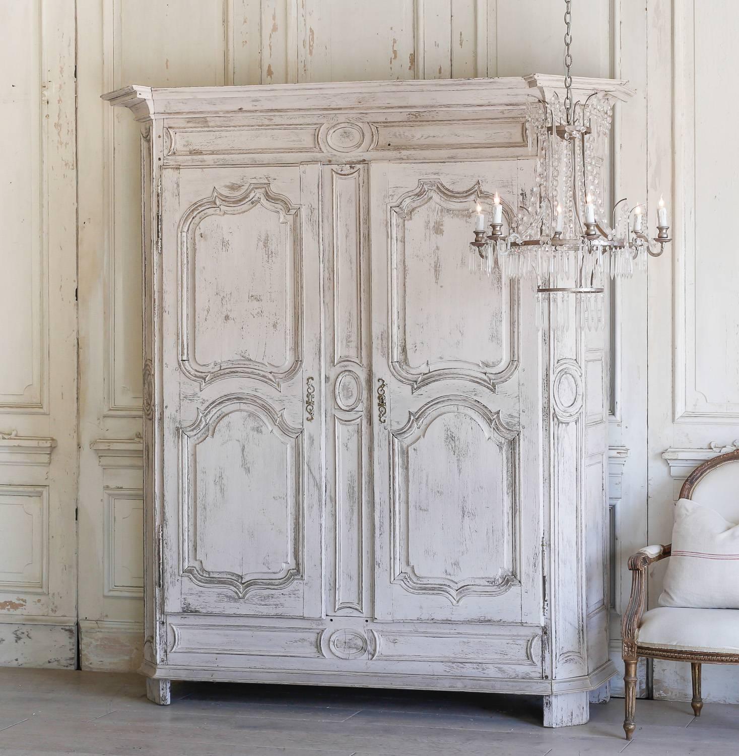 Antique armoire in a distressed, white blush color. This farmhouse-style armoire has four shelves measuring 24 inches deep. Clean medallion carvings decorate the unique exterior adding country charm to a bedroom or hallway.