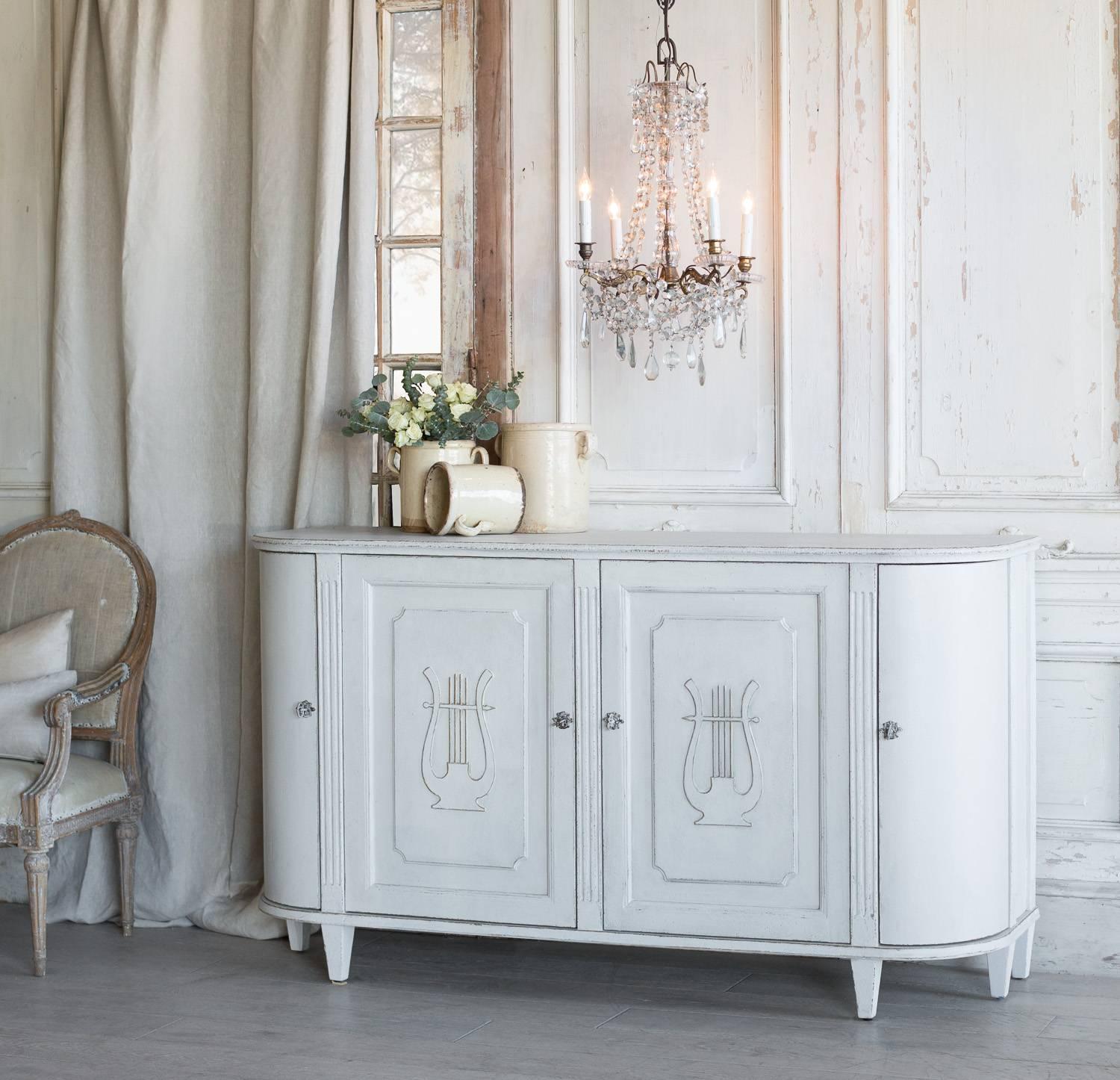 The lyre sideboard in distressed white finish is a re-edition of a Gustavian period antique. Gustavian furniture was heavily influenced by neoclassical motifs, such as the lyre, a mythological symbol of power and equilibrium. The delicate details on