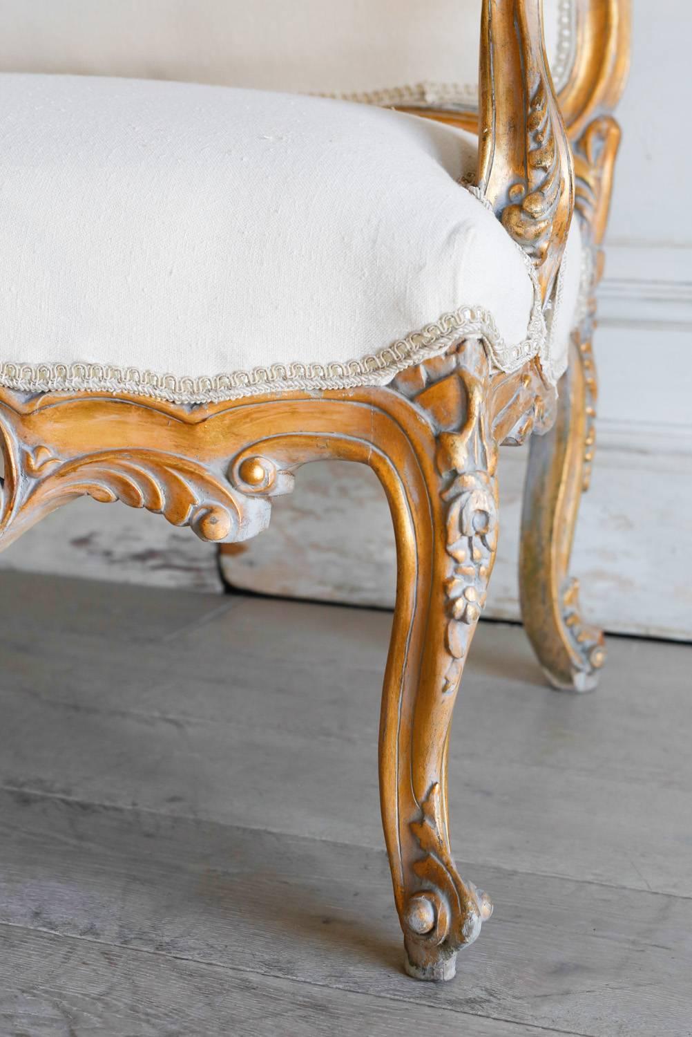 Stunning vintage settee in gilt with an elaborate and opulent ajouree carvings. Large central crest flanked by carvings in floral motifs along the backrest. All three aprons feature elaborate carved floral patterns as well as carvings on the Louis