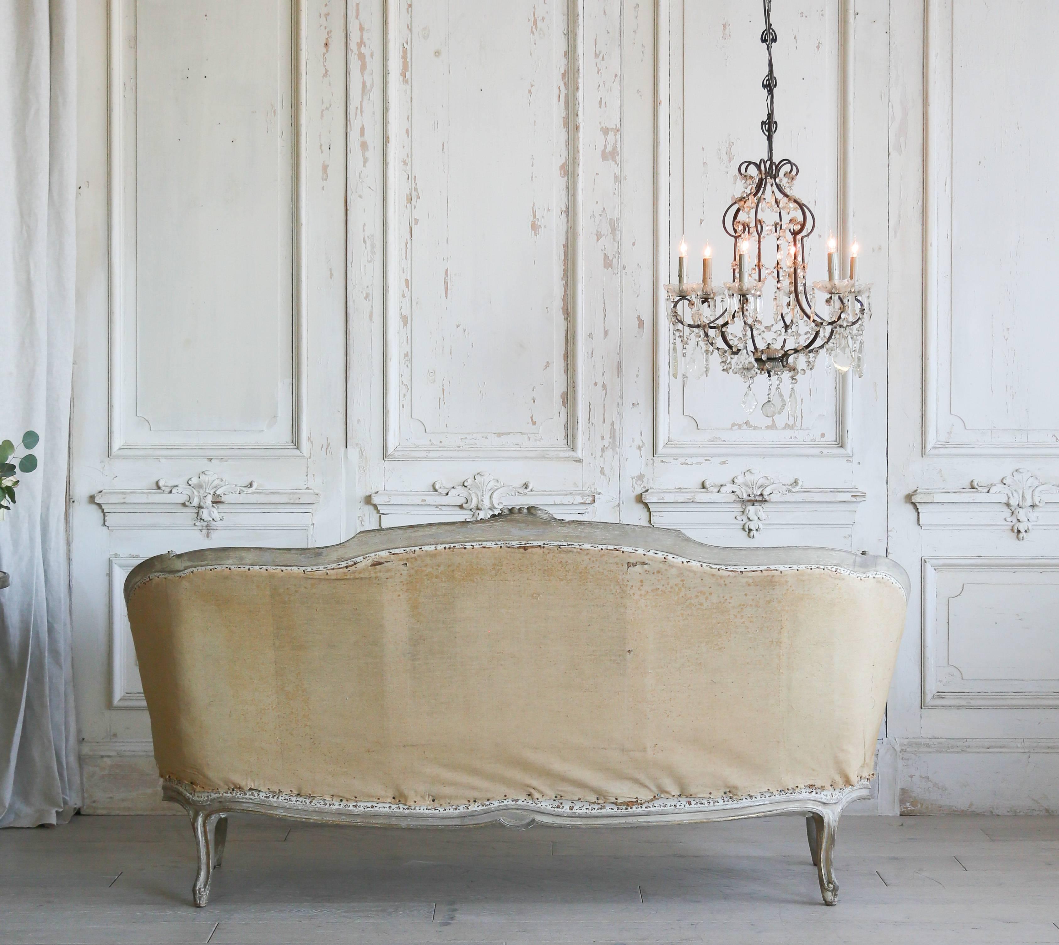 Delightful Louis XV daybed, circa 1880. The distressed bone finish with a hint of olive boasts carved details on the crest an apron. The intricate and delicate flowers make for a stunning piece. Original horsehair stuffing and fabric covering. A
