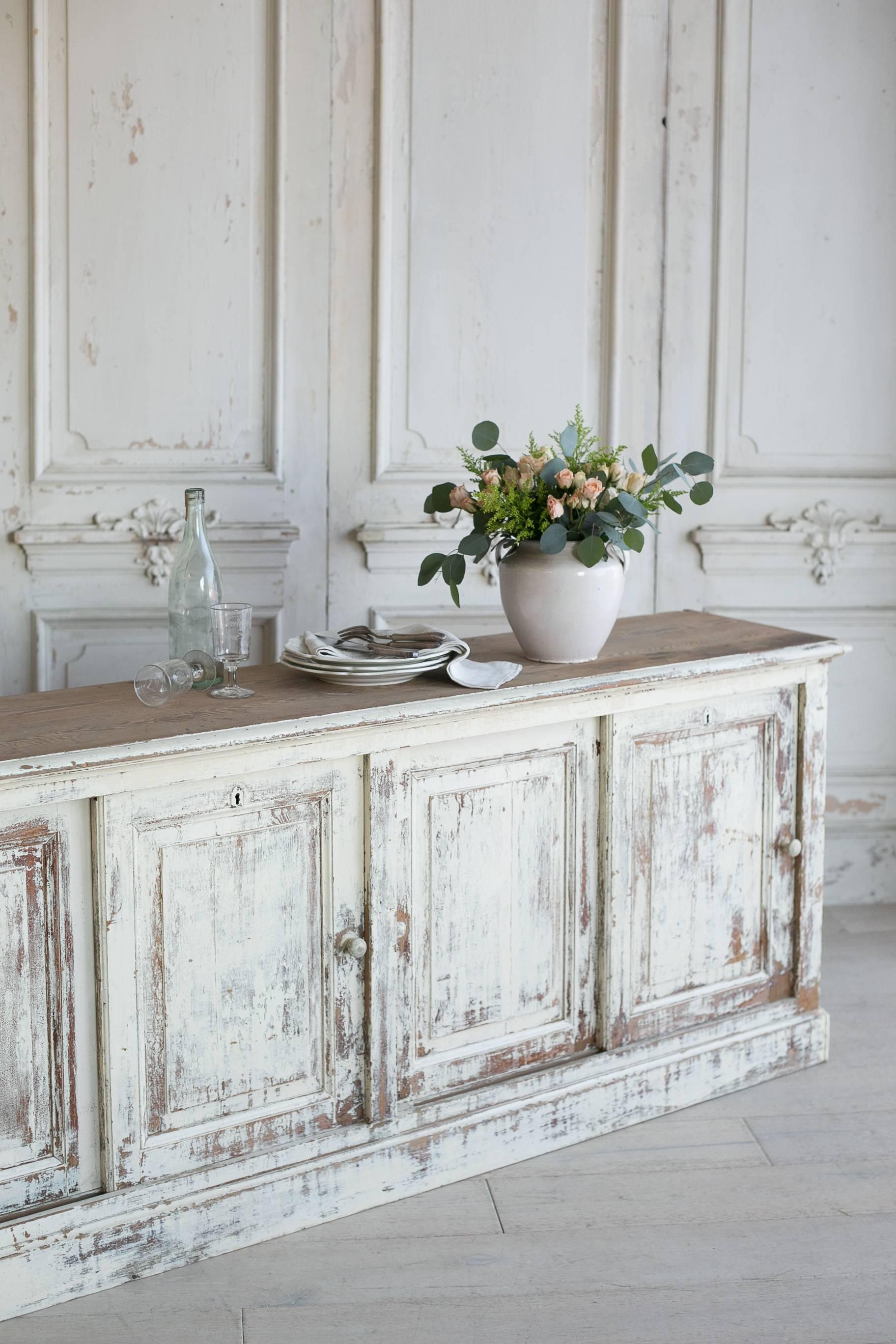 Stunning, extra long antique sideboard in distressed buttermilk finish. This narrow sideboard has an enormous amount of storage in the eight sliding cupboards presented counter style. Will add dramatic country farmhouse style to a dining room or