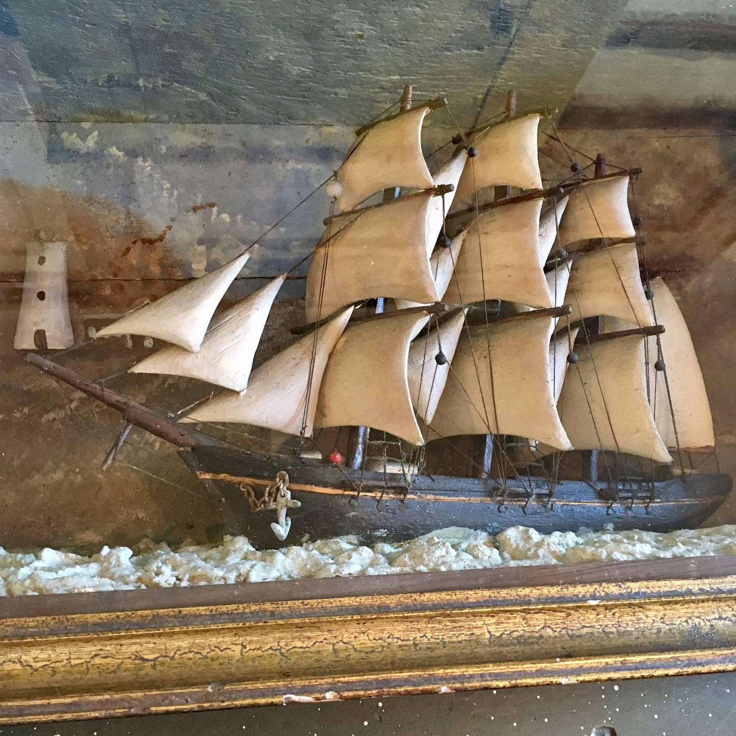 A 19th Century Nautical Shadowbox with hand carved ship in stormy seas on a
lee shore. The model has carved wooden sails, fully carved hull in black
paint, set on molded frothy rough seas. The painted background features a
lighthouse and cottage on