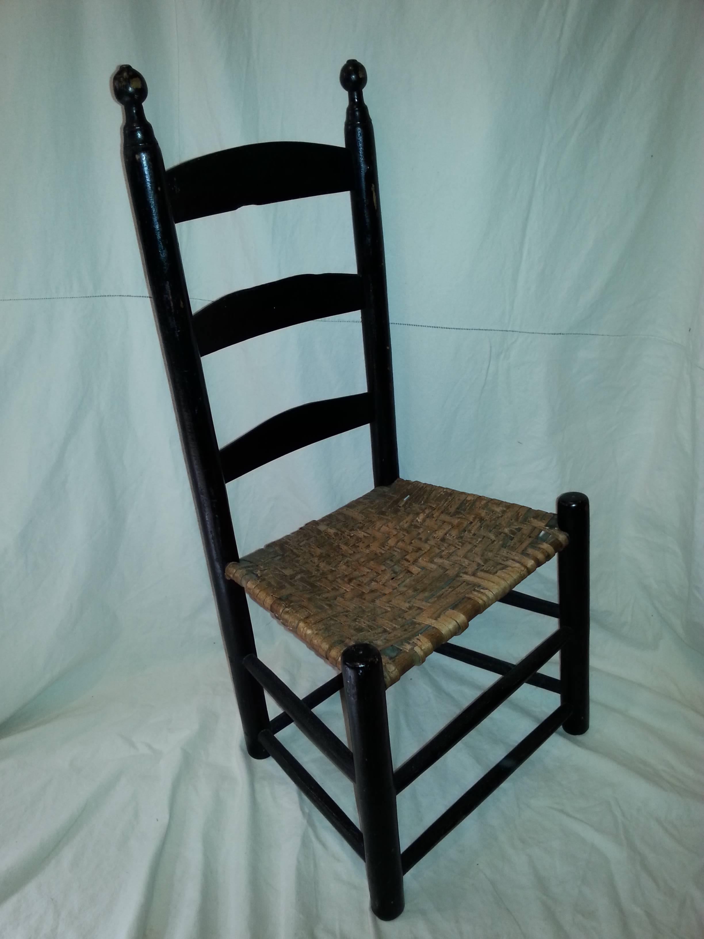 Painted black ladderback side chair with woven seat.