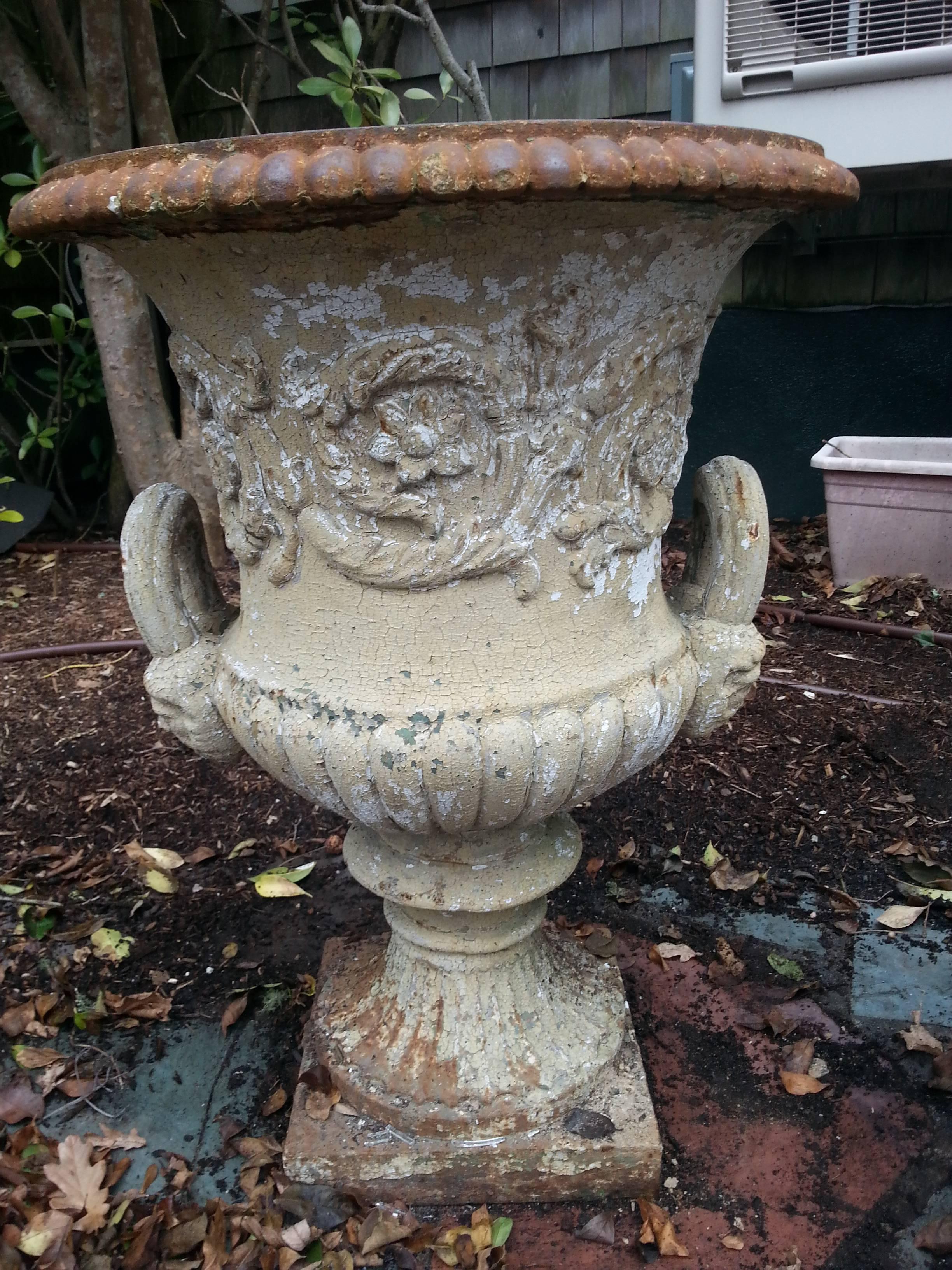 Iron garden urn with painted outside. Beautiful motifs with faces on handles.