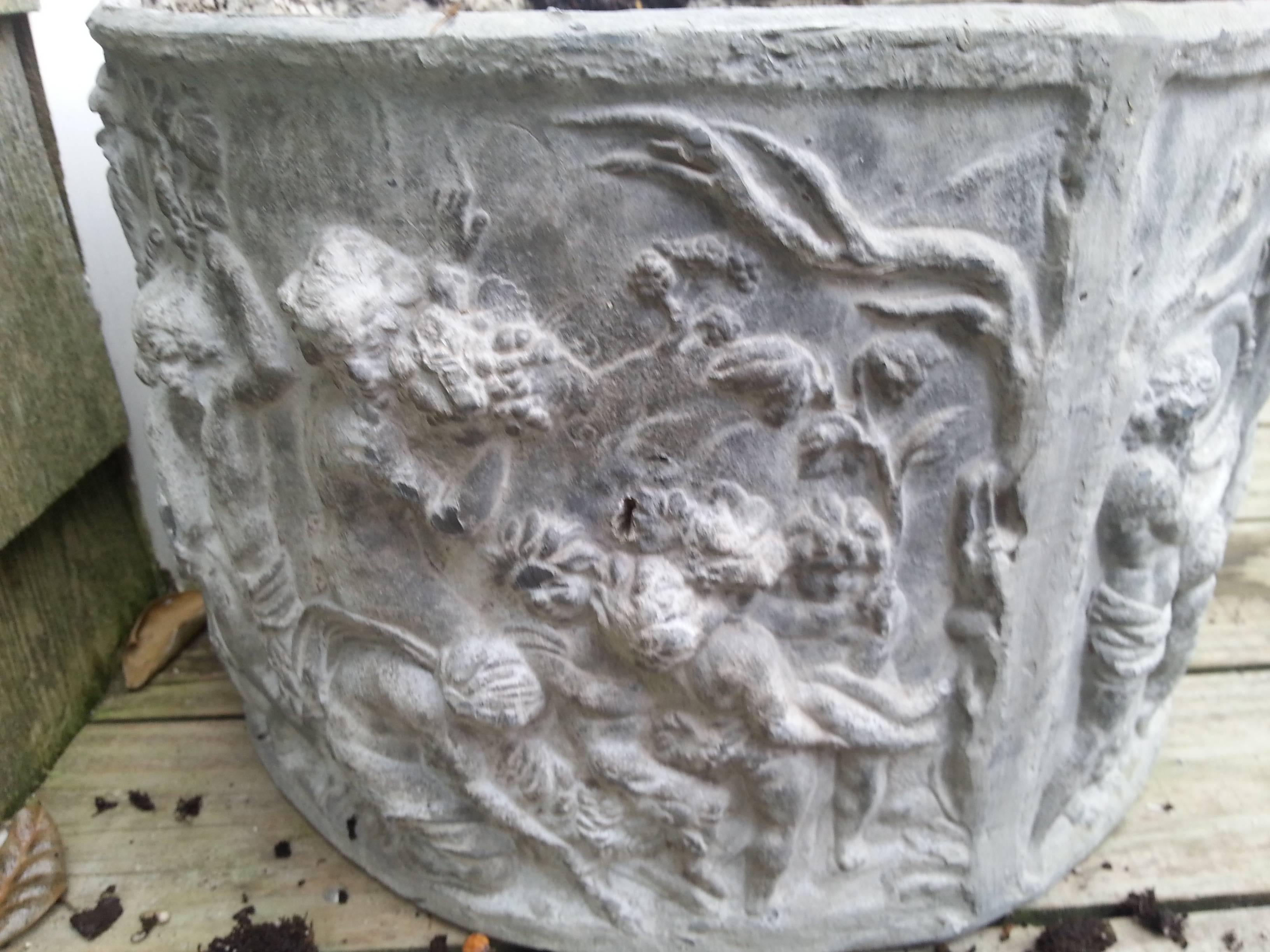 Circular lead planter. Beautiful angel motifs circle around exterior. Drainage holes in bottom.