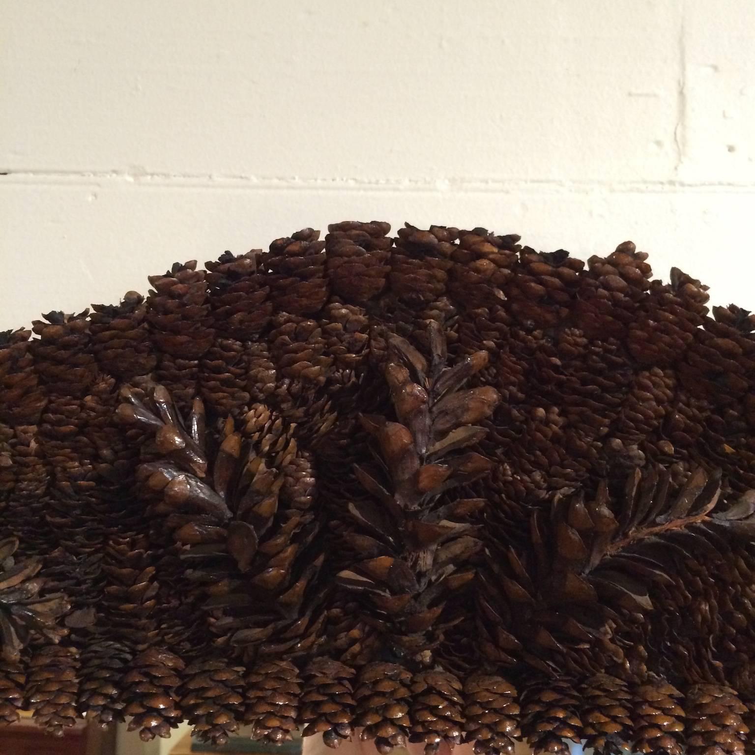 Mirror with frame embellished with natural pine cones.  Frame base is of wood.