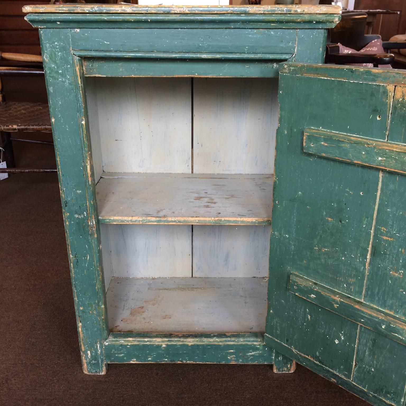 Armoire verte à une seule porte, avec des parcloses décoratives. Intérieur anciennement repeint.