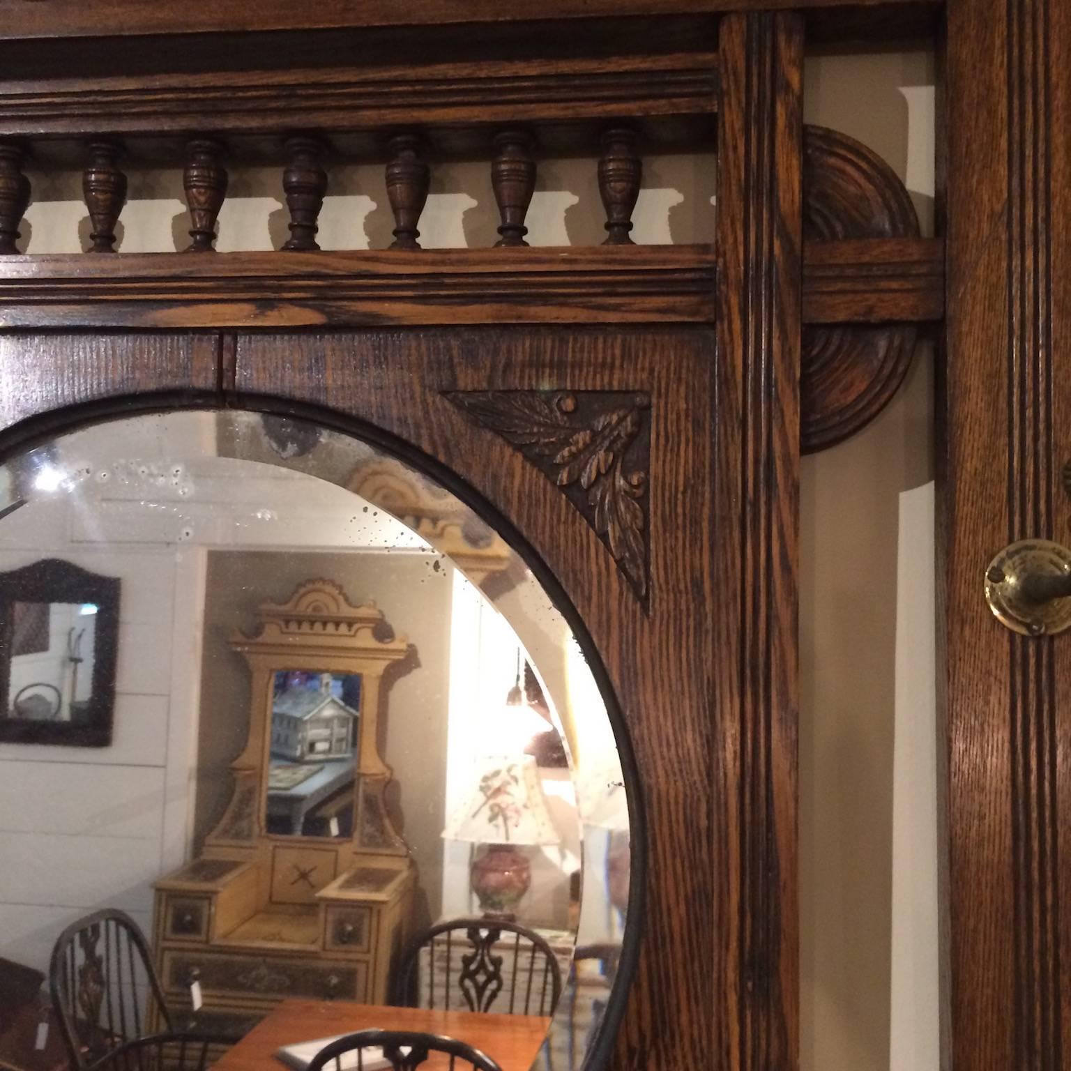 Beveled glass mirror with decorative oak frame and hat rack.