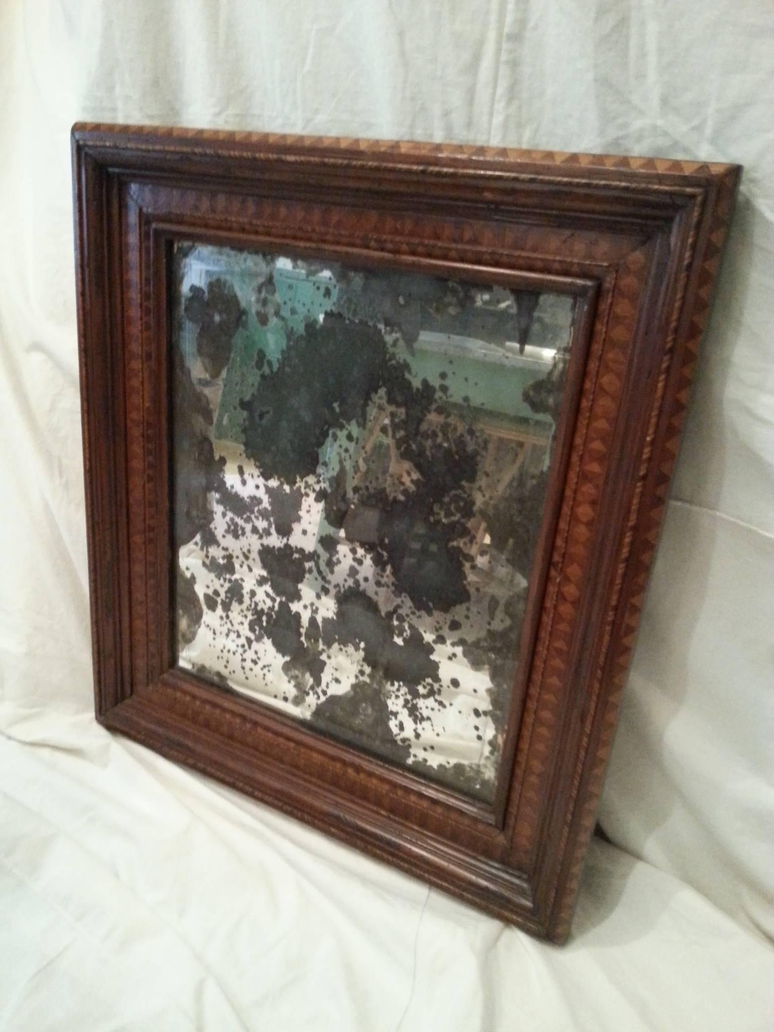 Marquetry frame constructed from varying wood species.  Antiqued glass mirror.