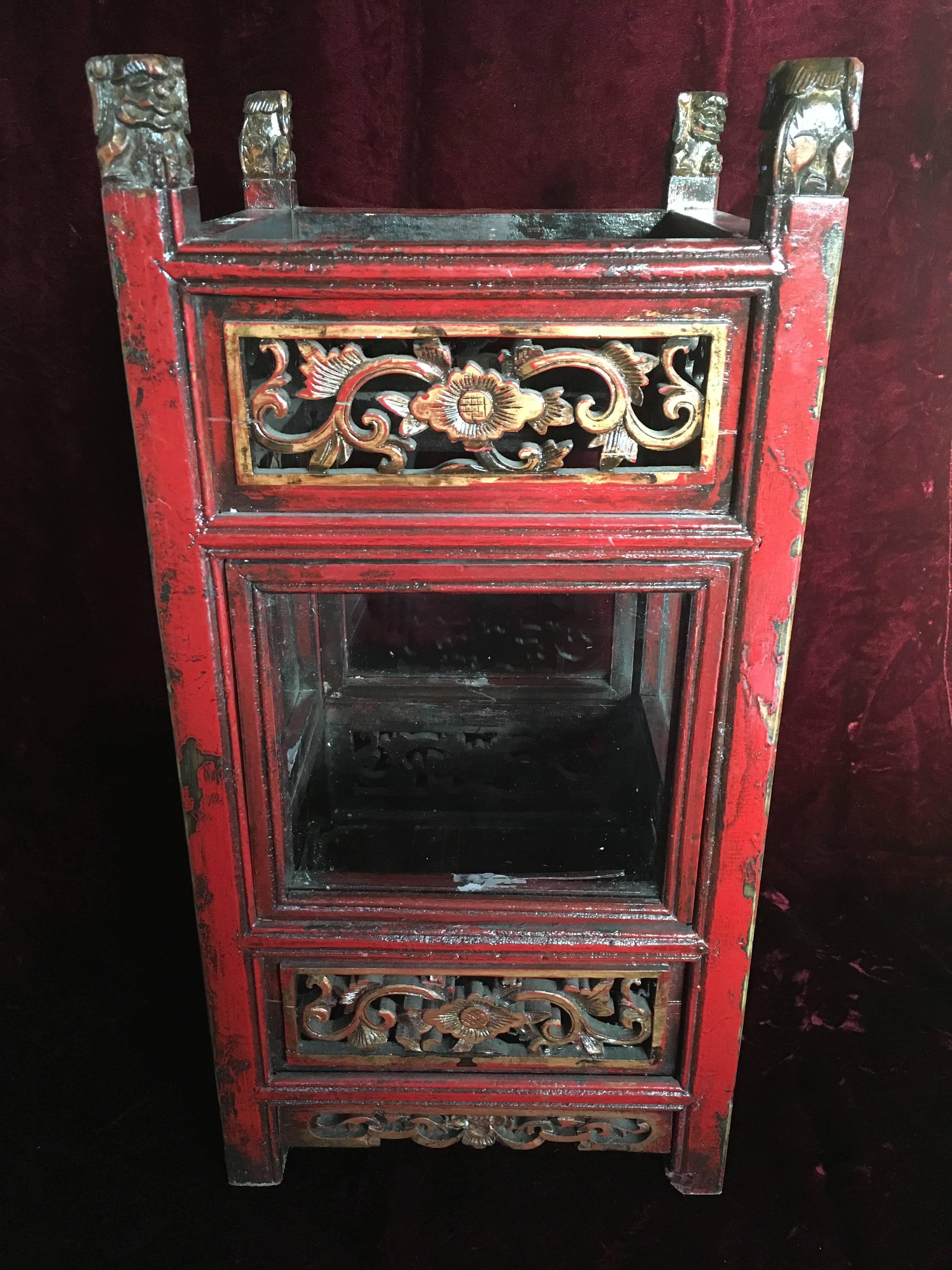 A pair of Chinese carved and painted wooden candle lanterns with glass panels, circa 1950, having carved Fu Dogs atop four posts, holding a carved and pierced arabesque floral panel above a glass panel, over another carved and pierced panel, raised