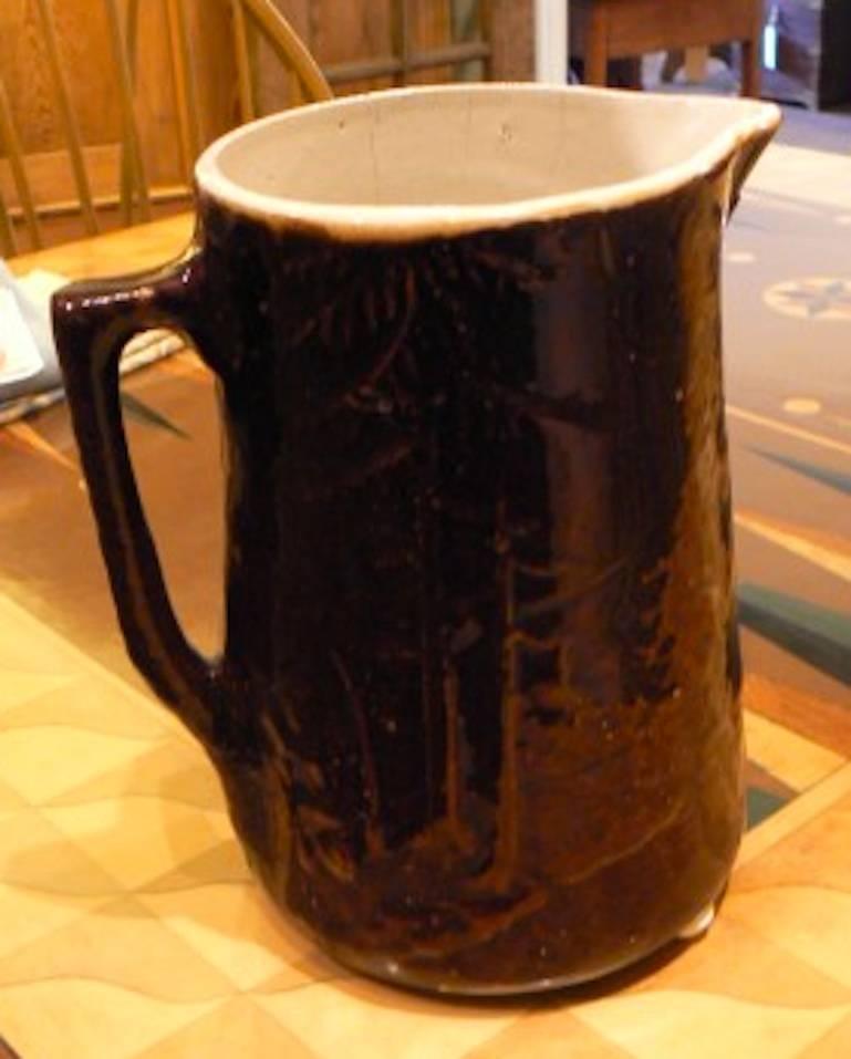 Pottery pitcher with stag relief in brown glaze finish.