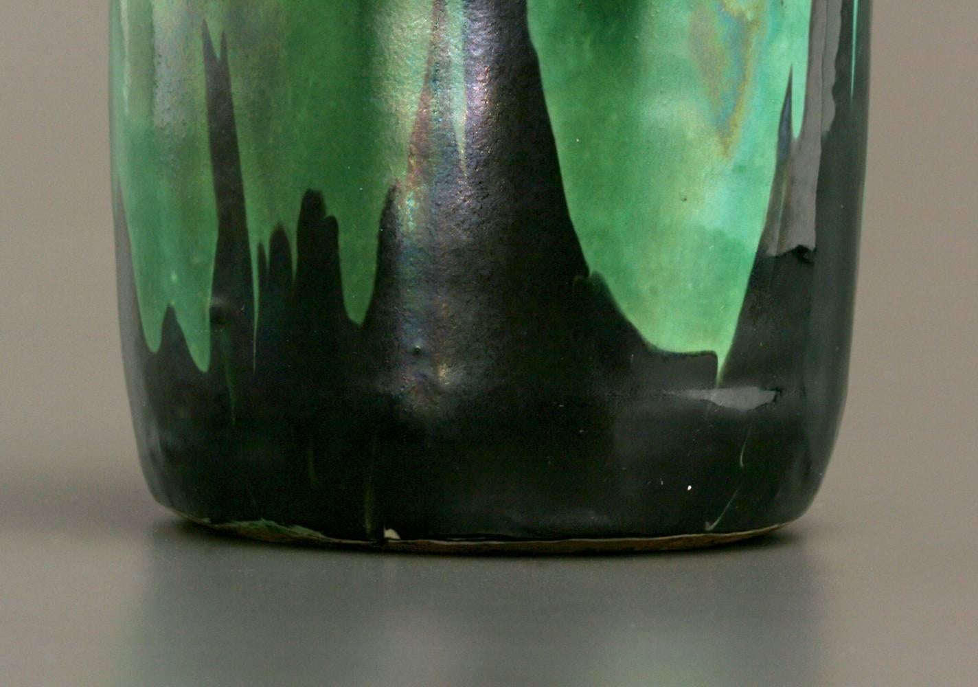 This astonishing stoneware vase with a lid was made by Max Laeuger at Tonwerke Kandern, Kandern, Germany. The tapering ovoid body is covered with satiny black and grass-green running glazes, a clear departure from the colored slip glaze decoration