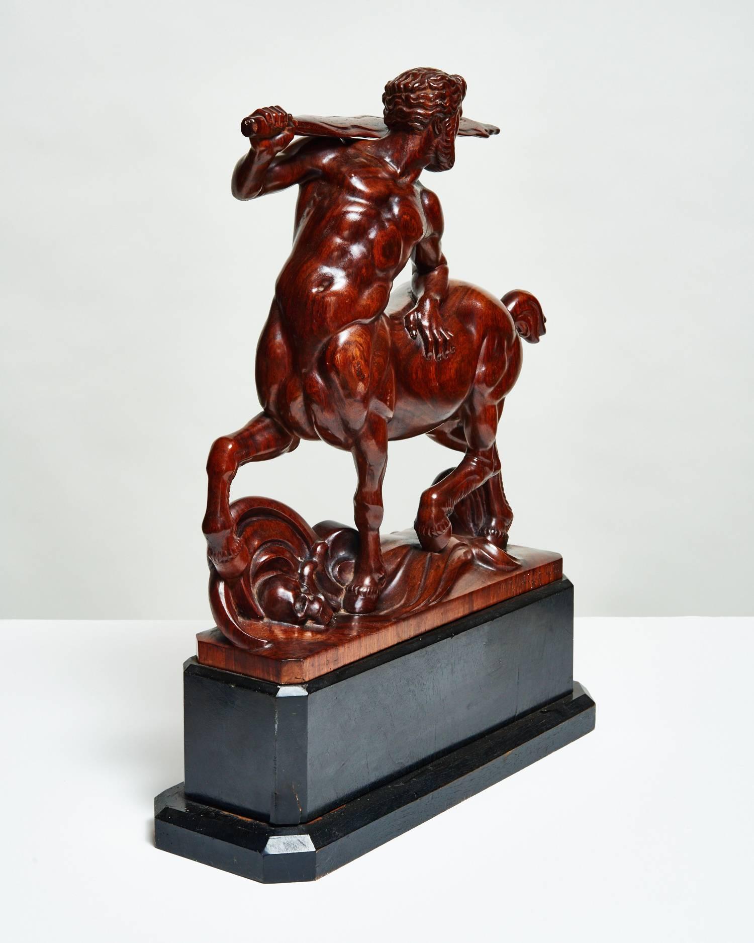 Carved from rich, warm maple wood and mounted on a large black stand with faceted edges, Hans Huggler-Wyss’ Maple Centaur sculpture is a powerful depiction of the half-man, half-horse mythological creature. The centaur carries a large spear that