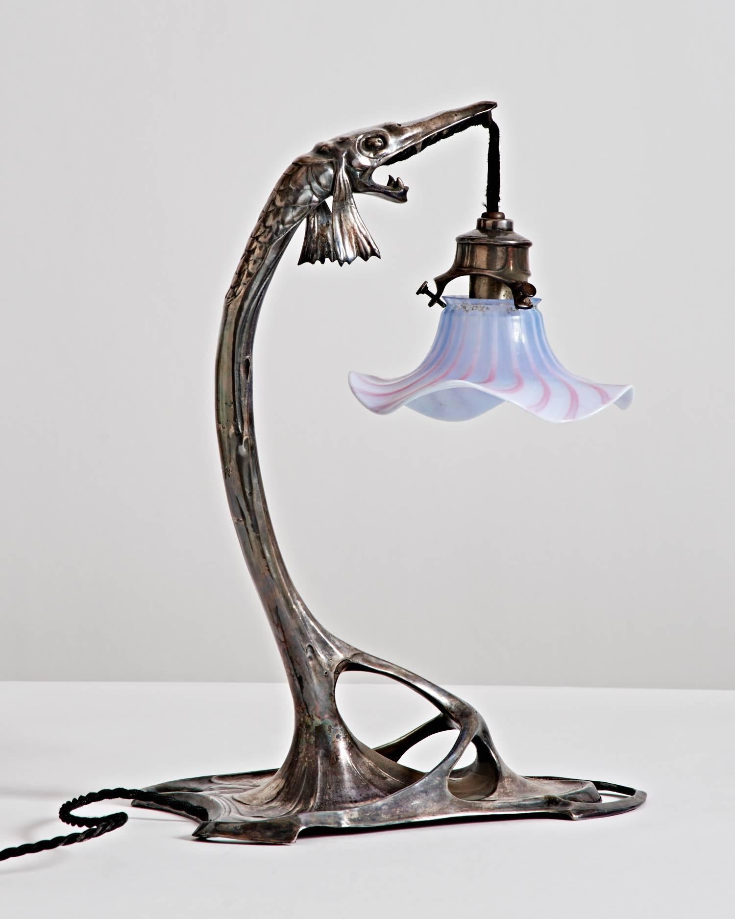 Jugendstil-Tischlampe aus Zinn in Form eines Hechtfisches, an dessen Maul ein geblümter Glasschirm hängt.