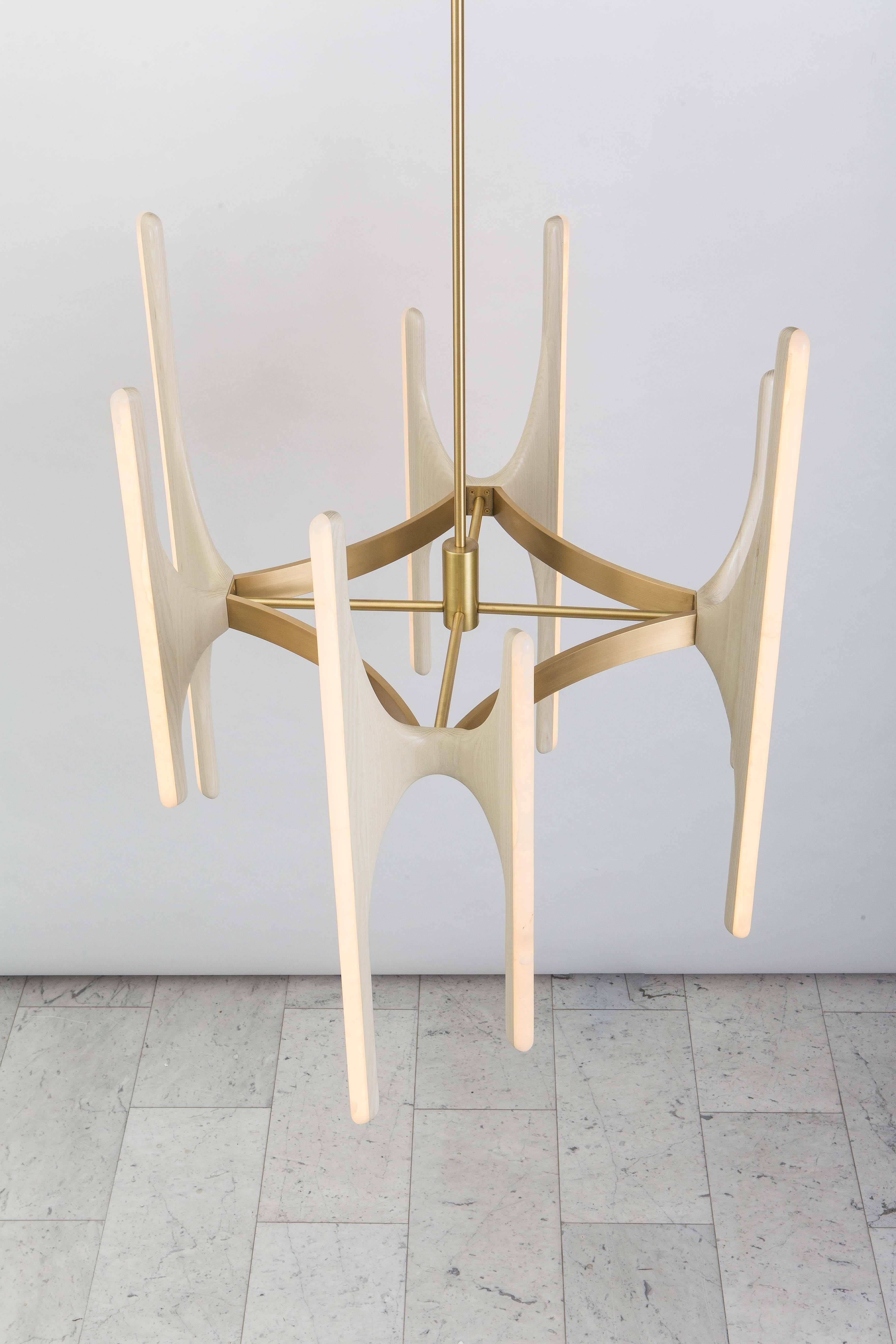 Inspired by nature and the human form, Haase’s custom chandelier is composed of hand-sculpted bleached ash “branches” imbedded with hand-carved white onyx that encase dimmable LEDs. Suspended upon a diamond-form satin-finish brass center structure,