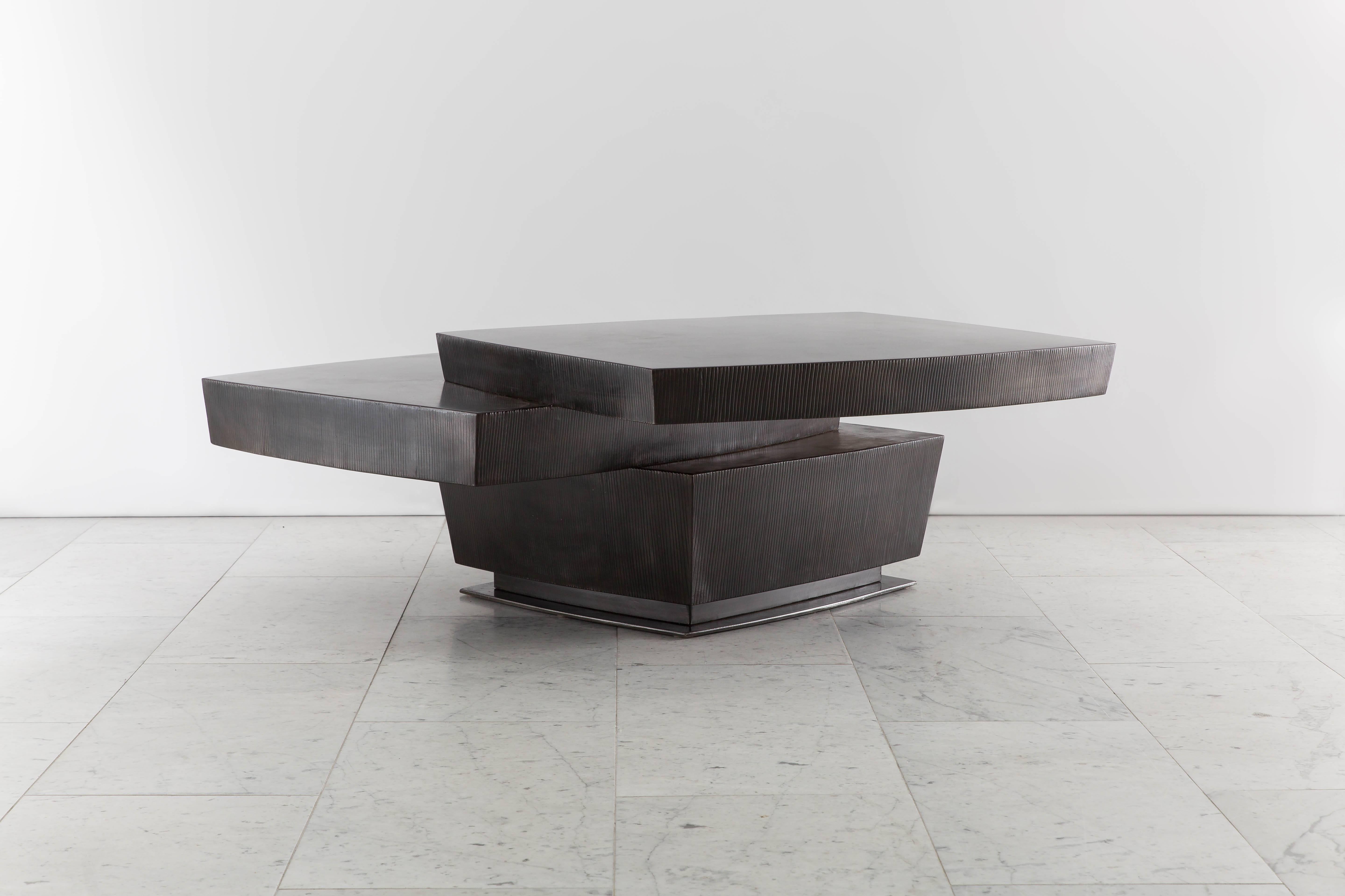 La table basse empilée en acier noirci de Gary Magakis, fabriquée à la main et unique en son genre, incarne l'approche distincte du sculpteur, qui consiste à créer des formes géométriques audacieuses et denses qui dégagent simultanément une