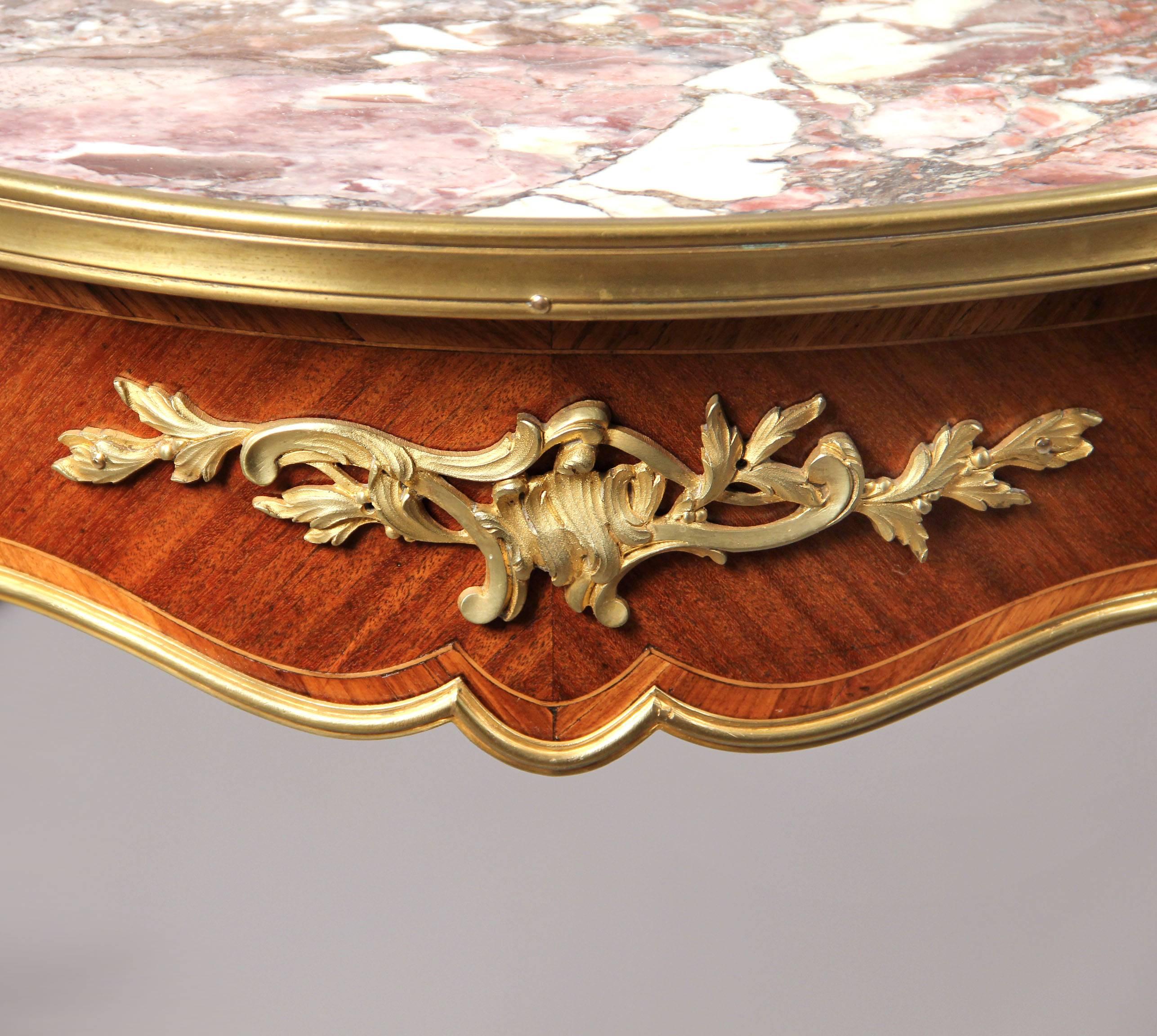 A late 19th century Louis XV style gilt bronze-mounted marble-top lamp table.

The shaped circular Breche Violette marble insert top, above a bronze mounted frieze, on tapering bronze mounted legs and scrolled acanthus sabots.
