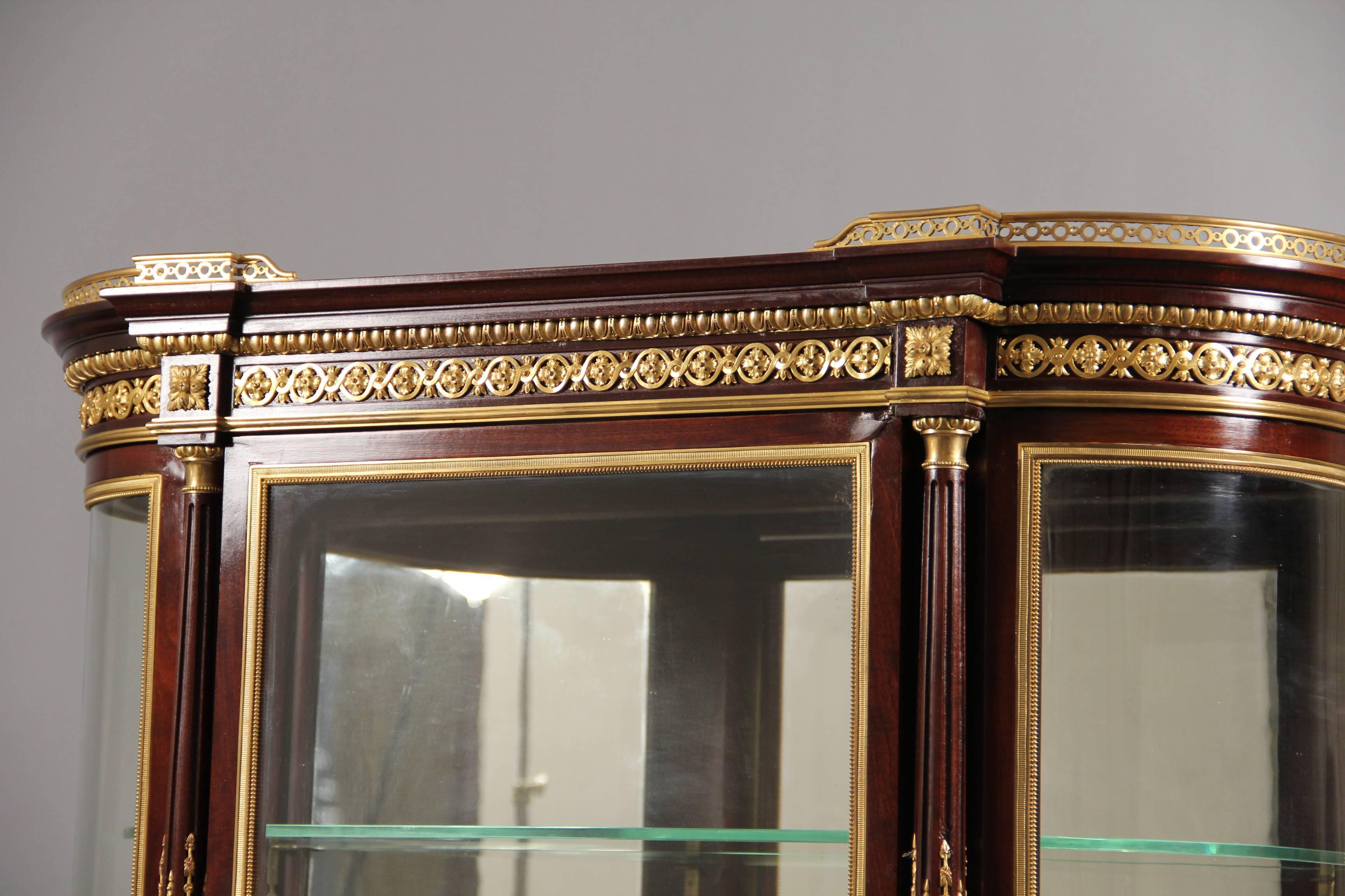 A late 19th century Louis XVI style gilt bronze-mounted parquetry vitrine cabinet.

by Paul Sormani.

The vitrine of demilune form. The top with a central door and beveled glass above a single drawer. The bottom as a storage cabinet.

Signed