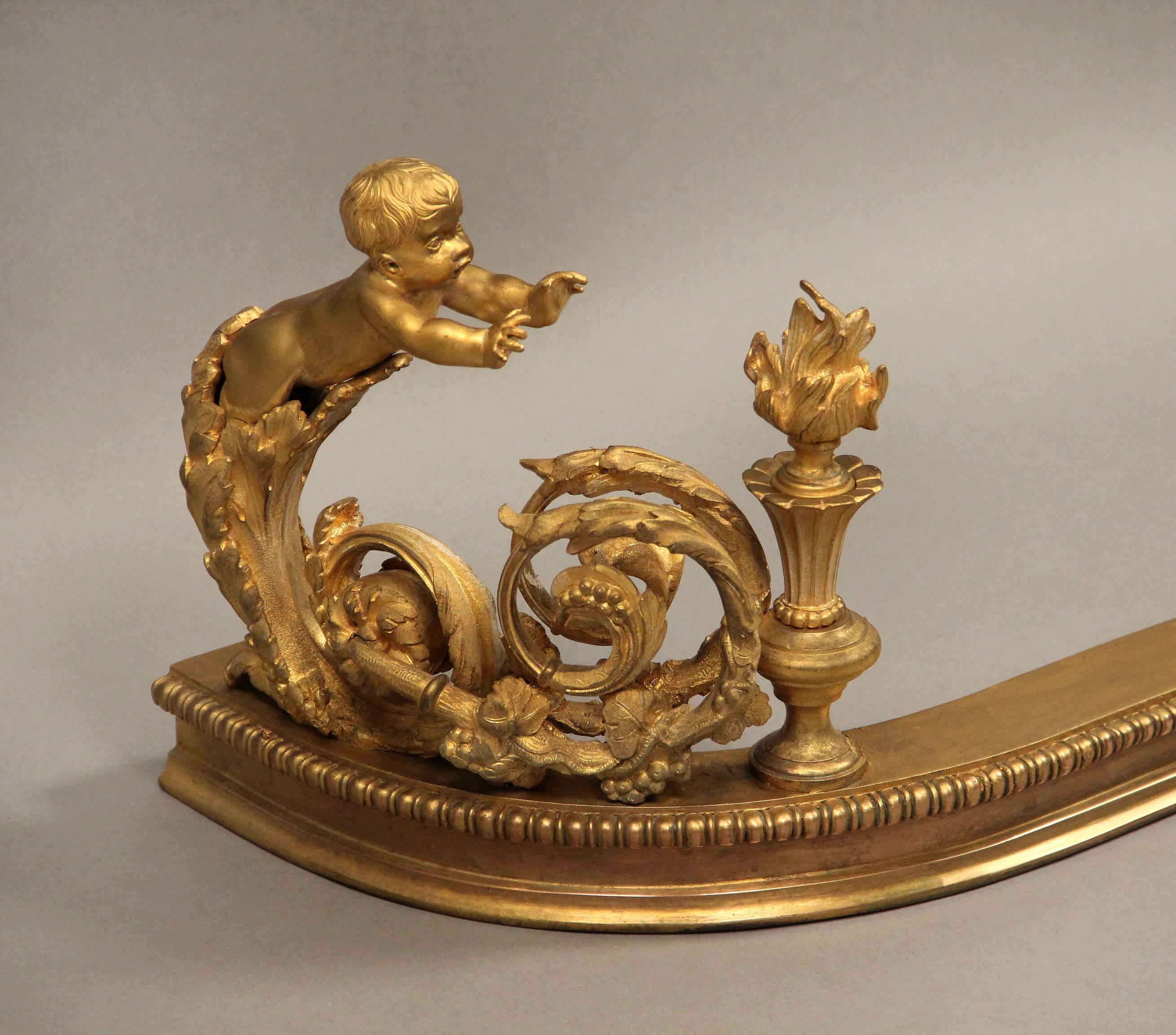 A very fine late 19th century gilt bronze fireplace fender

The centre of the fender with a wreath and scrolling foliage with berries, each end with a child reaching toward a flame for warmth.