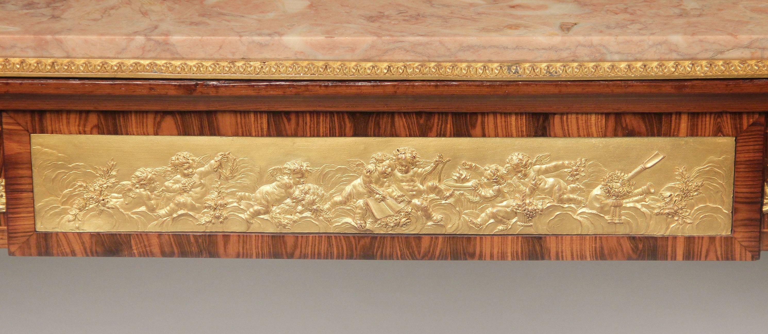 A very fine late 19th century Louis XVI style gilt bronze mounted occasional table.

The rectangular marble top above a frieze drawer centered with a bas-relief plaque cast with music-making putti, with a simulated drawer to the reverse, the sides
