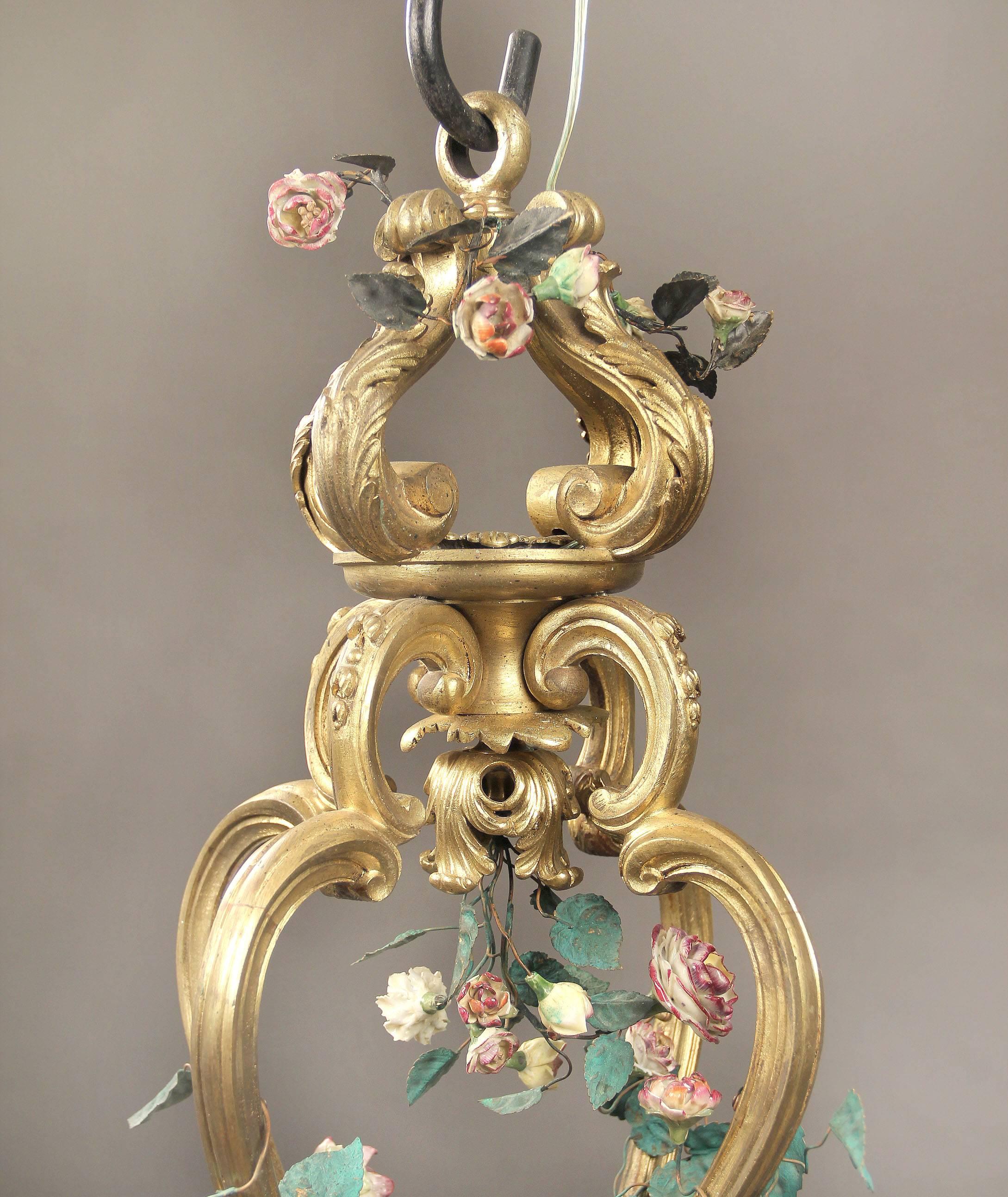 A late 19th century gilt bronze and French porcelain Rococo Revival eight light chandelier porcelain flowers and leaves drape the bronze frame with pink and yellow roses covering the eight perimeter lights. If you are looking for a chandelier, a