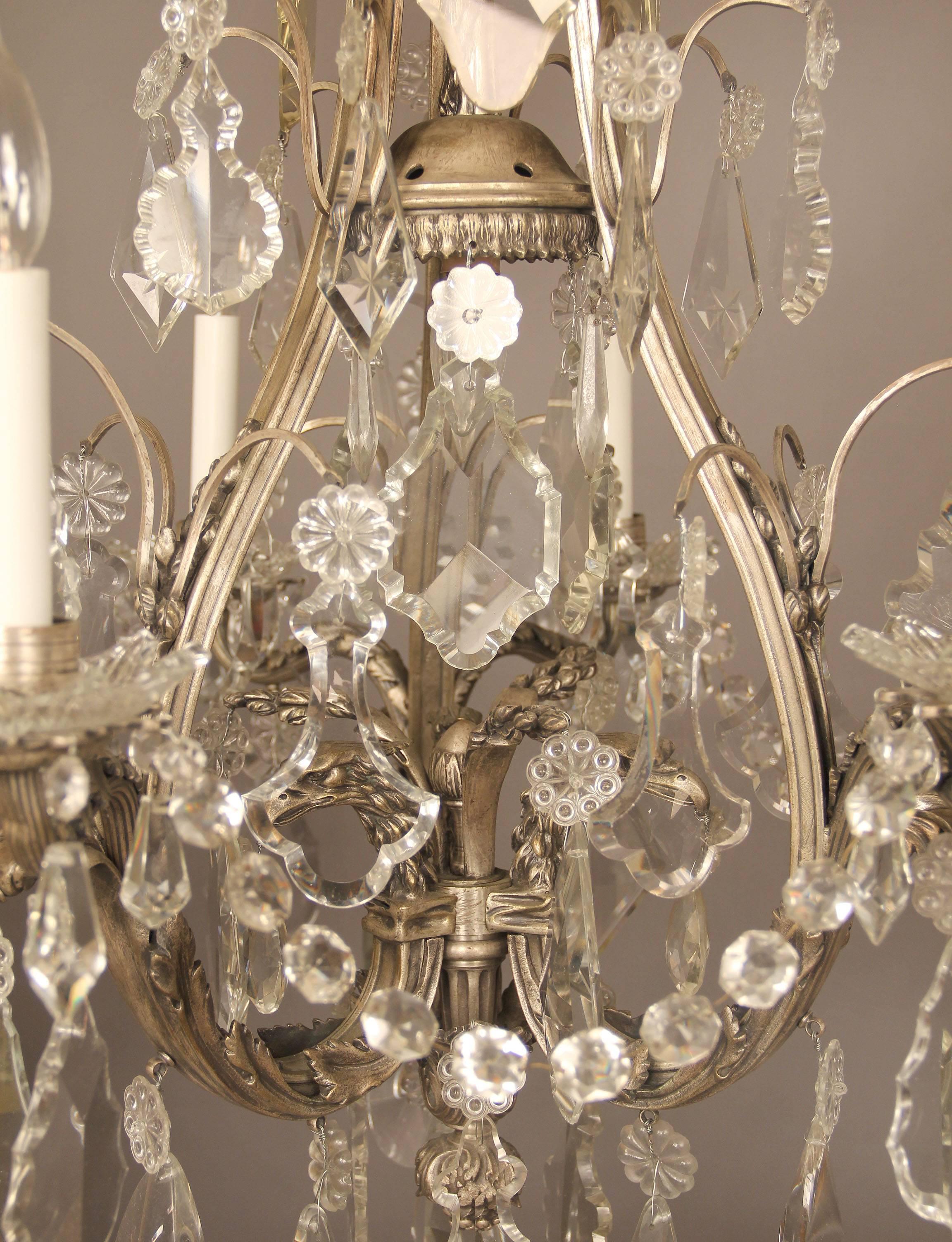 An exceptional late 19th century silvered bronze and crystal six light chandeliers.

Multifaceted and shaped crystal, central column with three eagle heads, top dome with floral and curtain designs, six perimeter lights with bobeche