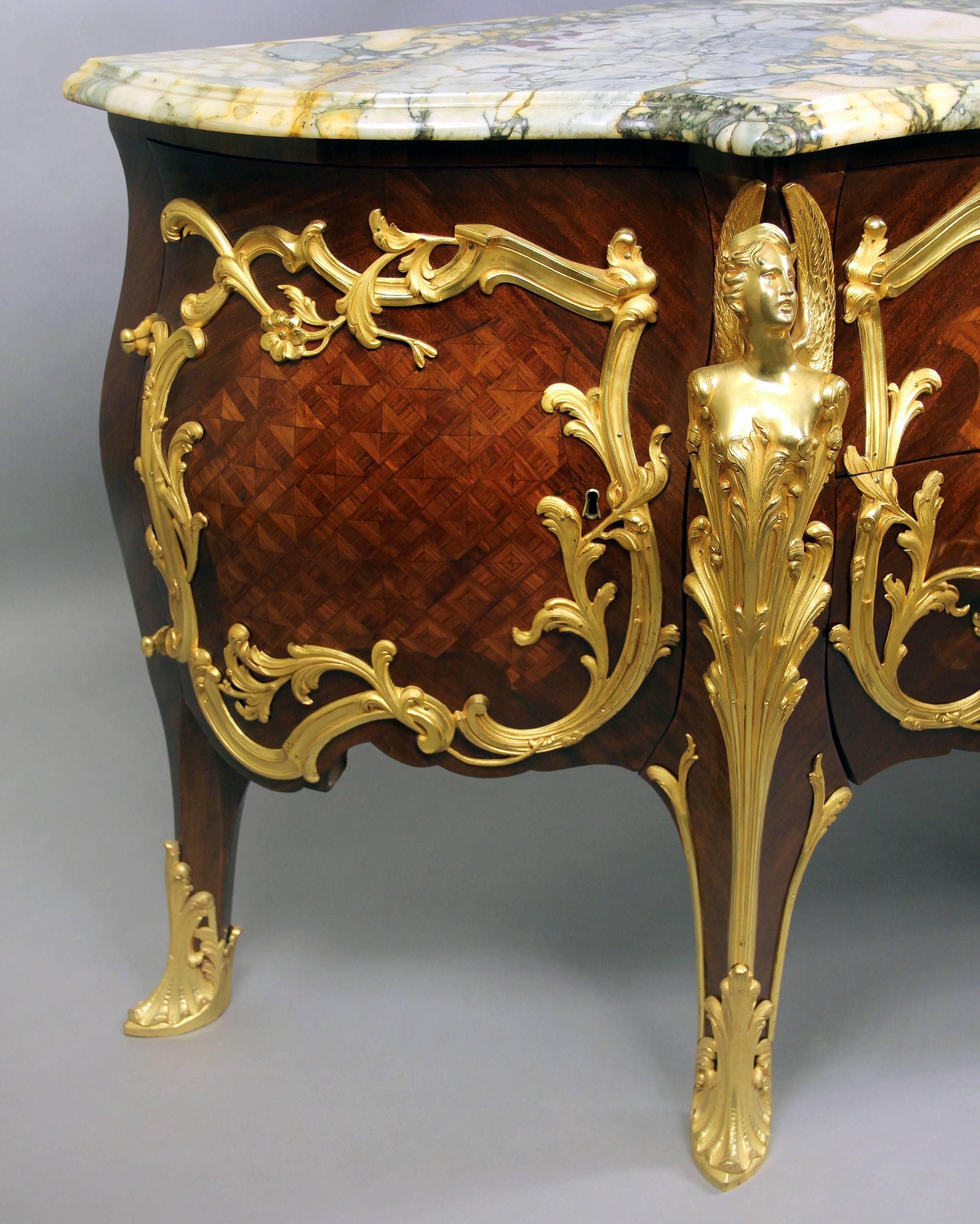A lovely late 19th century Louis XV style gilt bronze-mounted and parquetry inlaid commode.

Surmounted by a serpentine veined marble top, the conforming case of bombe outline fitted with deep drawers flanked by winged caryatids and enclosed