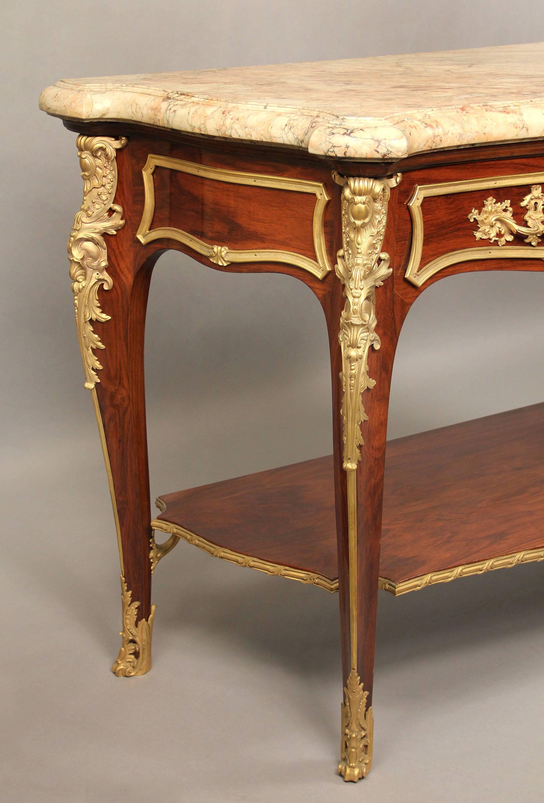 An extremely fine late 19th century Louis XV style gilt bronze-mounted server or console.

The shaped marble-top above two drawers, the bronze-mounted tapering legs joined by a bronze-mounted shelf.