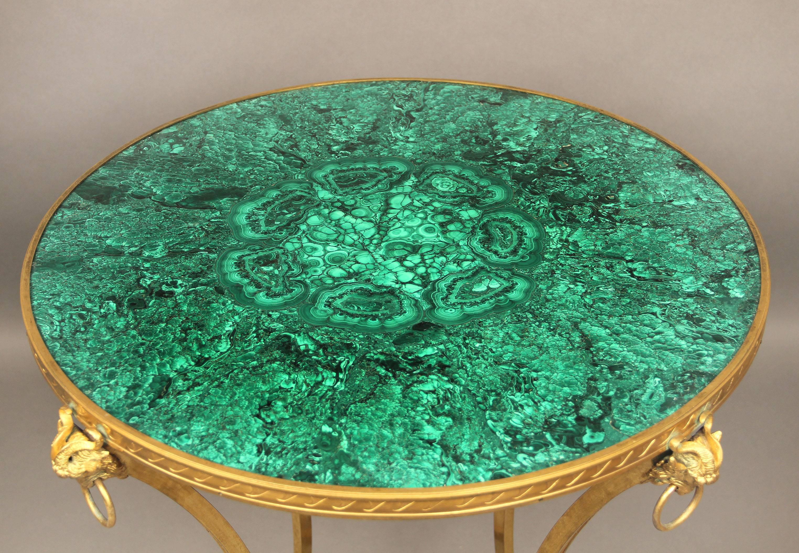 A late 19th century gilt bronze and giltwood mounted Empire style malachite lamp table. 

Beautiful malachite top above gilt bronze ram head mounts, giltwood stretcher joins the bronze legs.
 
Malachite is a semi-precious stone and also a