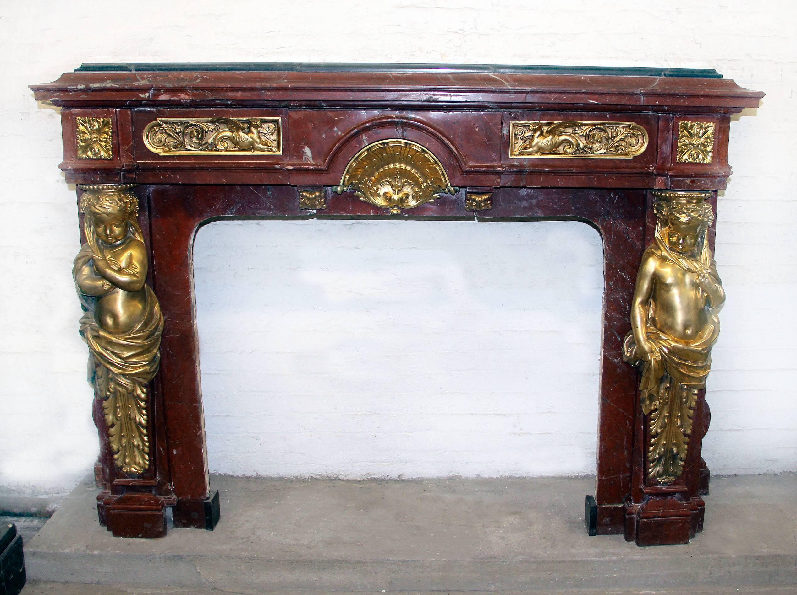 A very fine and palatial late 19th century gilt bronze-mounted rouge royal marble fireplace

A thick and heavy marble frieze with two gilt bronze plaques with griffins and scrolling foliage and centered with an inverted sea shell design. The legs