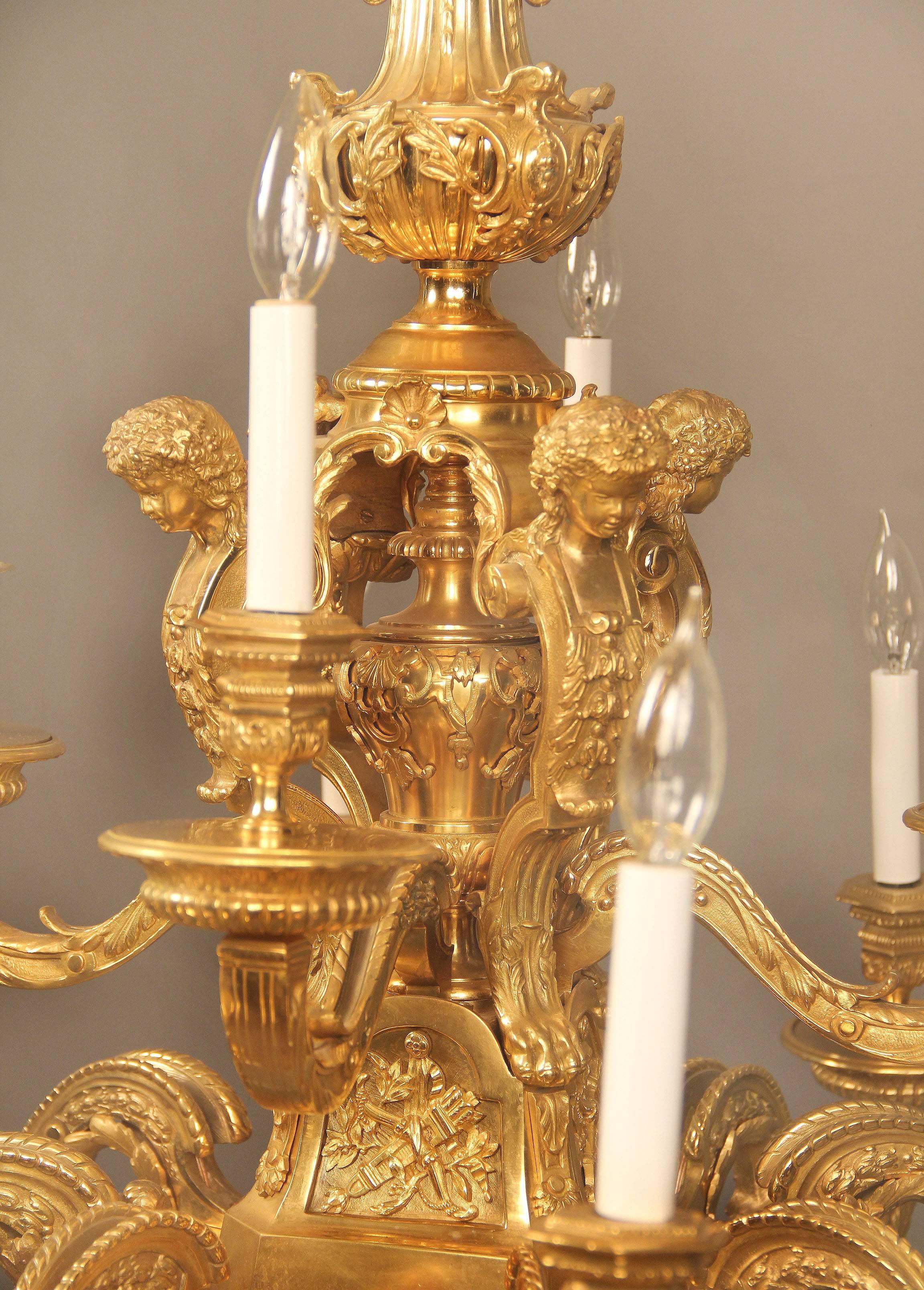 An excellent quality late 19th century gilt bronze 12-light chandelier

The superb all bronze casted frame with foliage and trophy designs along the body and arms, the centre of the body with four cherub busts and four female faces along the base.