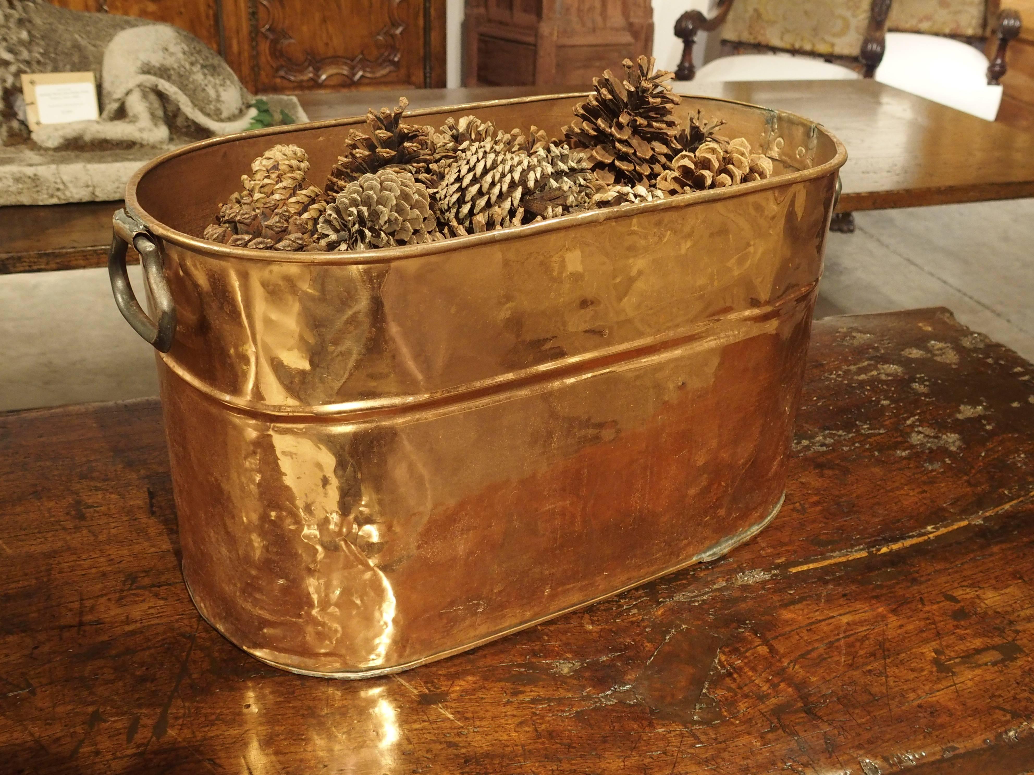 This large antique French, oval, copper container is just the right size for displaying anything from dried flowers to toys. Other uses can be storage for small kindling wood, a wine cooler or as a planter. Versatile in its uses, this antique French