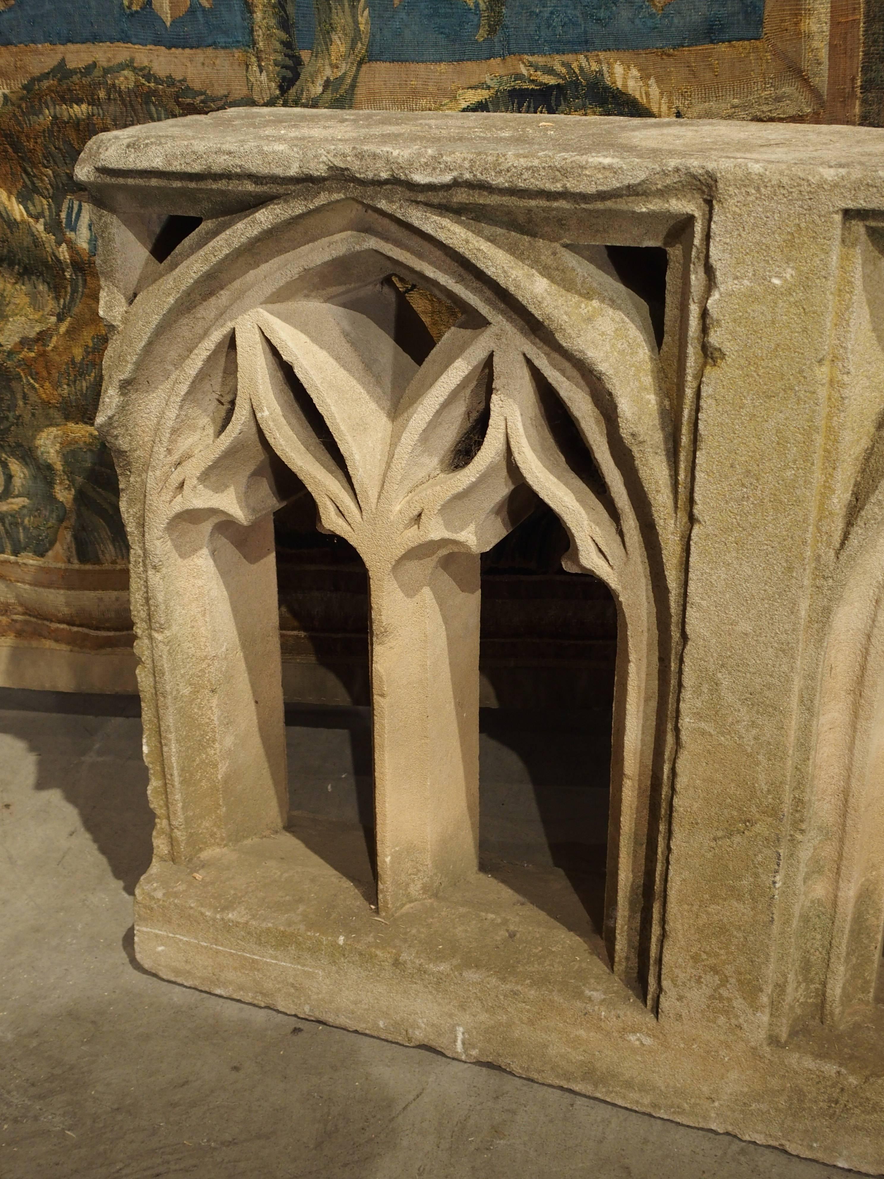 This rare antique French Gothic fragment was once part of the decoration on an 18th century stone building in France. It features a pointed arch with pierced designs on columns and a base. Once a single element, it is now in two pieces. Antique