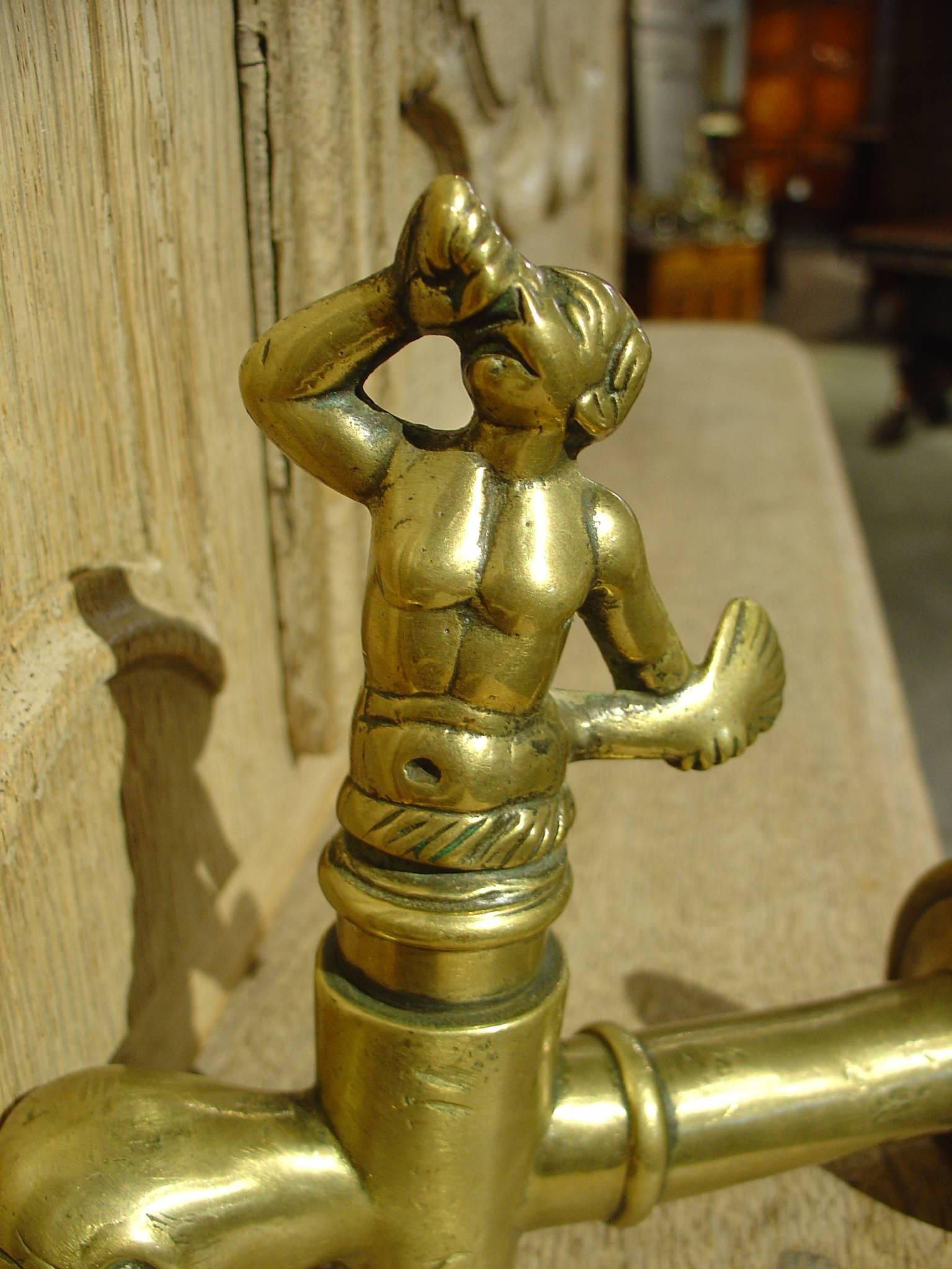 This spectacular antique French bronze spout depicts Triton holding his conch shell skyward, while his moveable tail turns the spout on or off.  He is seated upon a stylized dolphin which connects to the wine keg, fountain back, sink backsplash,