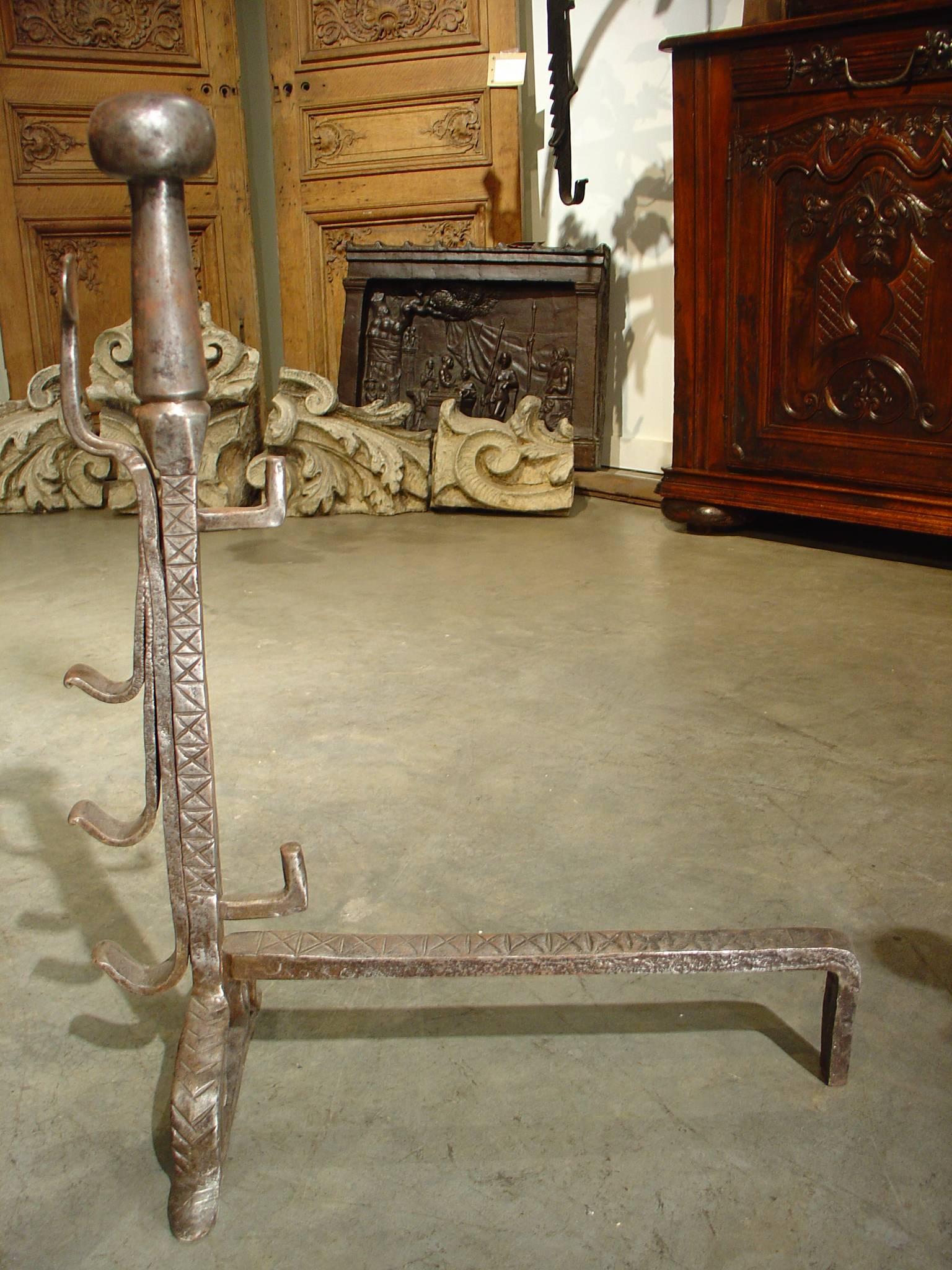 These antique French hand wrought andirons date to the 1500’s. With their age, they have become beautifully worn.  They have levels of hooks for rods to be placed horizontally so the cooking pots could be hung at different heat levels.  The andirons