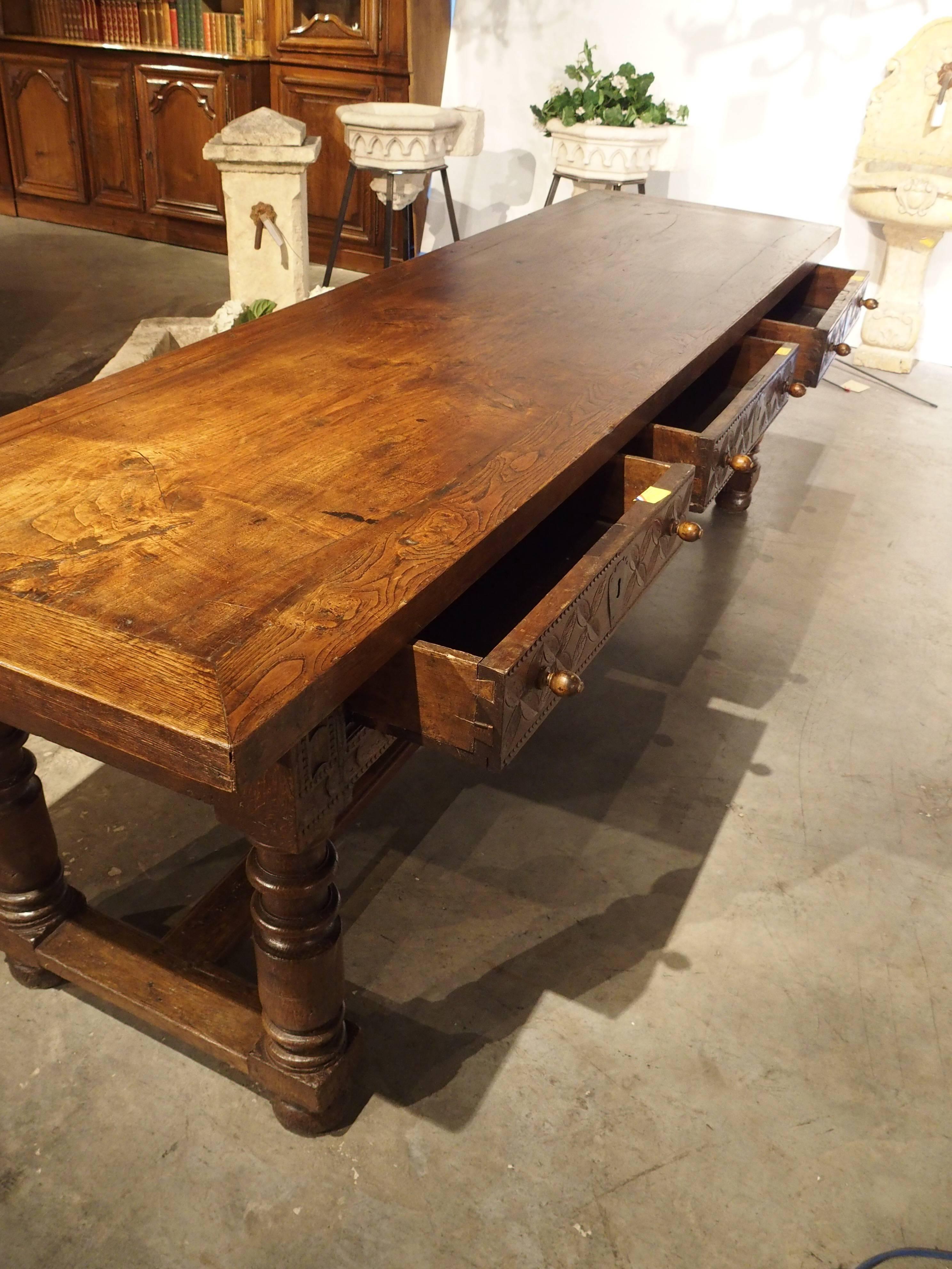 This wonderful antique refectory table from Spain dates to the 1700’s.  The apron has three drawers with two knobs per drawer as pulls. The front and back portions of the apron have motifs of floret and varying linear scoop motifs. There are four