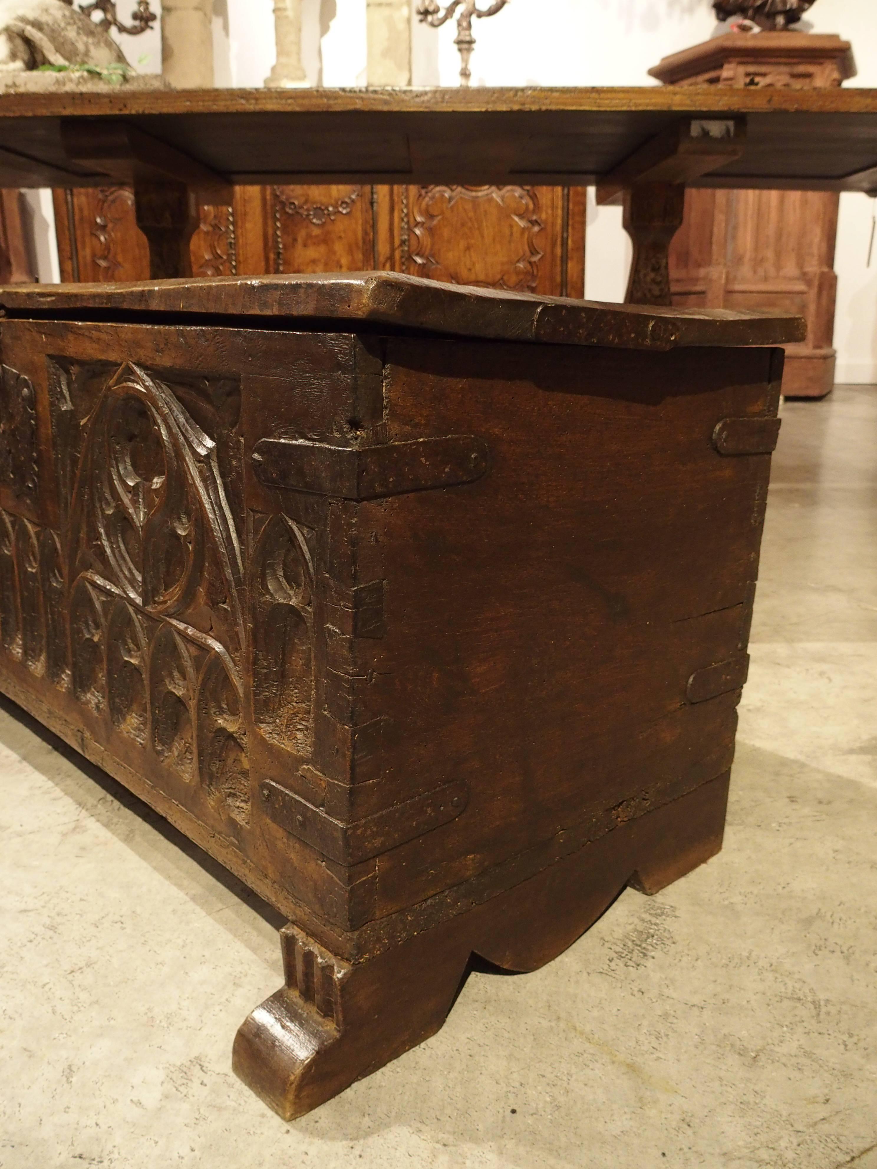 This French Gothic style walnut wood trunk dates to the 1600s. There are motifs of cusps, tracery and arcading on the front. The sides and backs are plain and the feet are shaped platforms with triglyph motifs on the front. It has its original iron