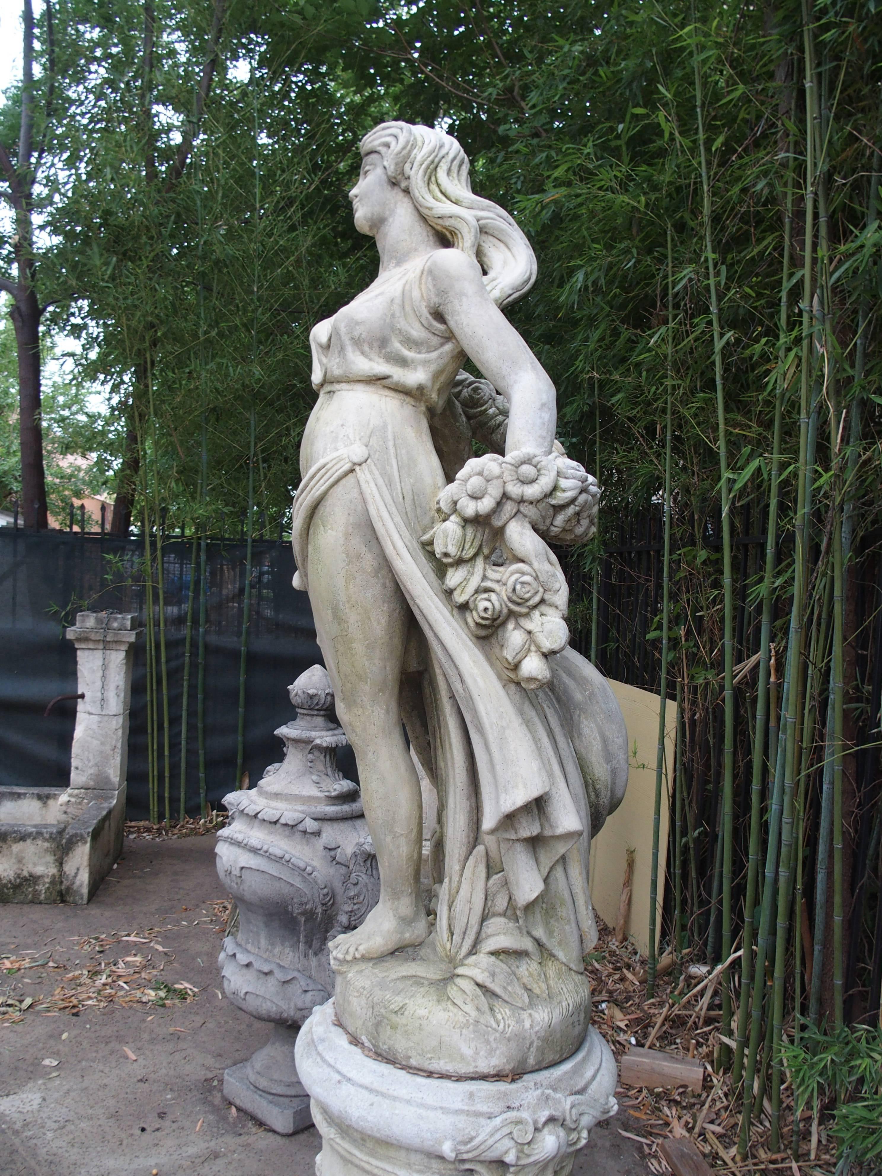 This beautiful French, life-sized statue depicts a woman in Roman style costume, striding confidently with her long hair, dress and a garland of roses flowing to the back. This French stone statue could be used indoors or outside and would be a