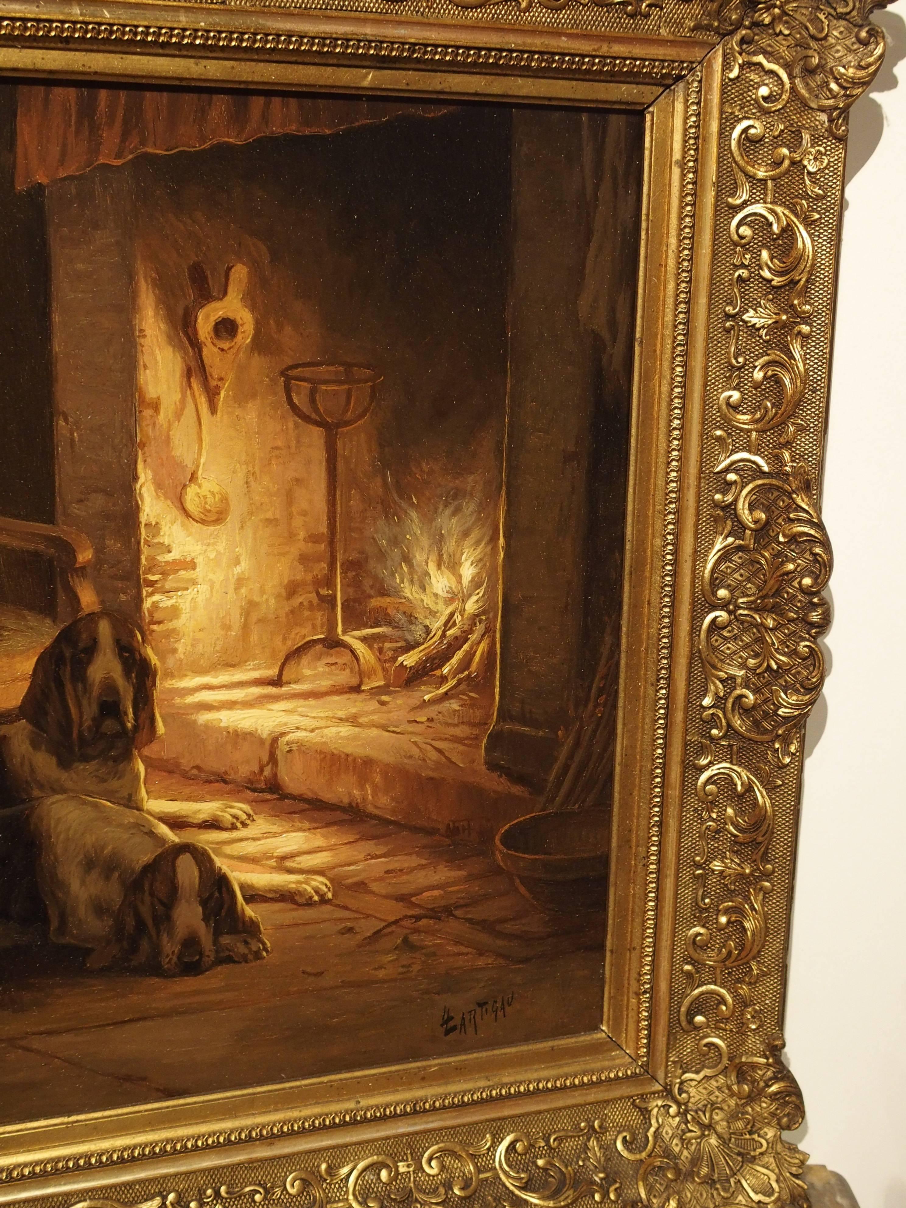 This fabulous antique French oil on canvas depicts a cozy interior scene with three hunting dogs warming up in front of the fire. The artist’s use of light in this painting is superb. The light coming from the fire in the stone mantel highlights the