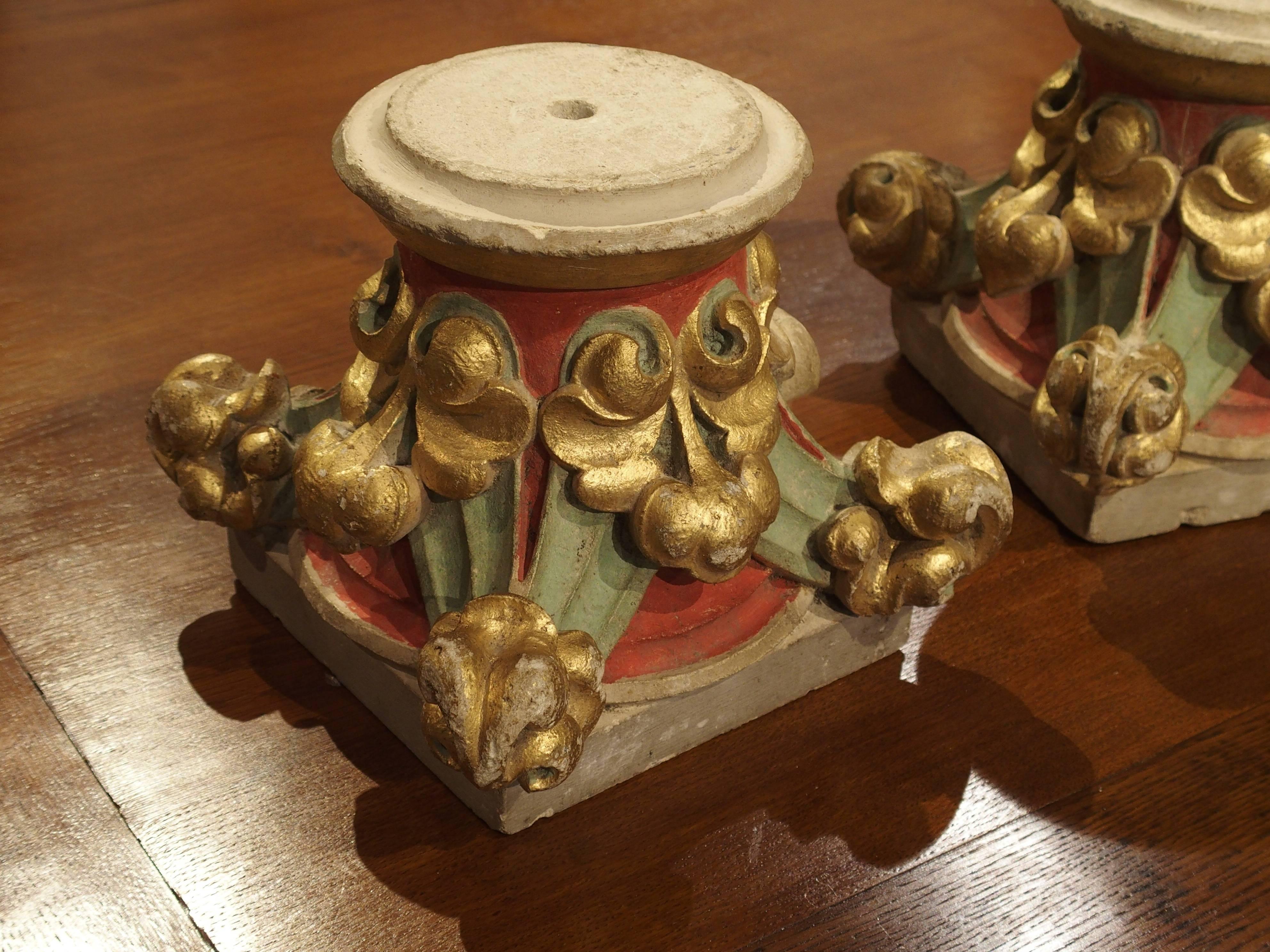 This interesting pair of small antique French stone capitals has been carved and painted with gold, aqua and red. The capitals rest upon a circular base which most likely would have been placed into columns of some sort. The tops are square and