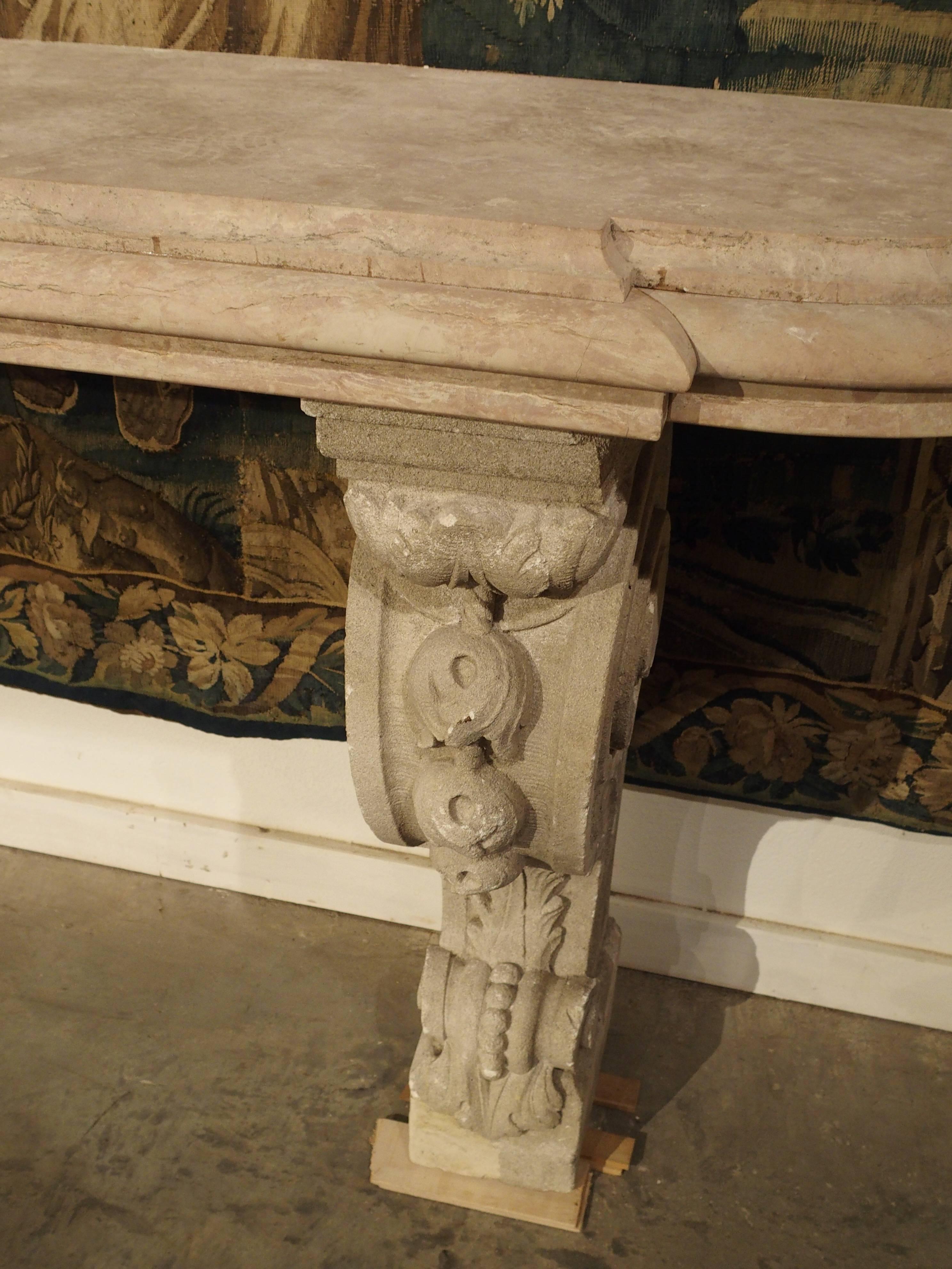 This elegant French honed marble-topped console has stunning, exaggerated and volute shaped legs made of reconstituted stone. There are motifs of acanthus leaves, flowers and beads on the volutes. In France, this console is called a console