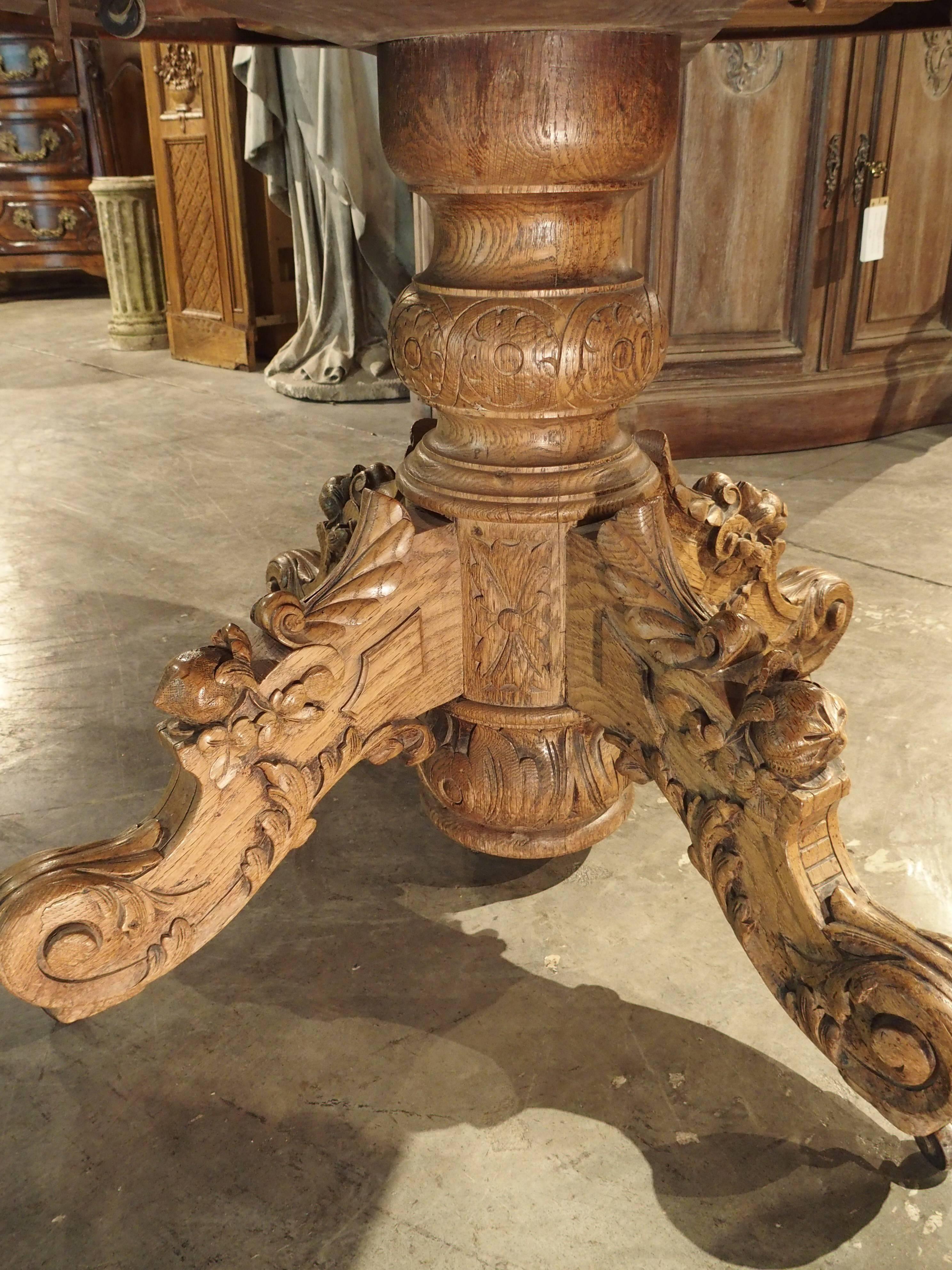 This French oval table has been constructed of European oak. It has a shaped and carved round center post with four richly carved legs on rollers. The carving is exquisite and includes acanthus leaves, fruit, guilloche and more. At one point in