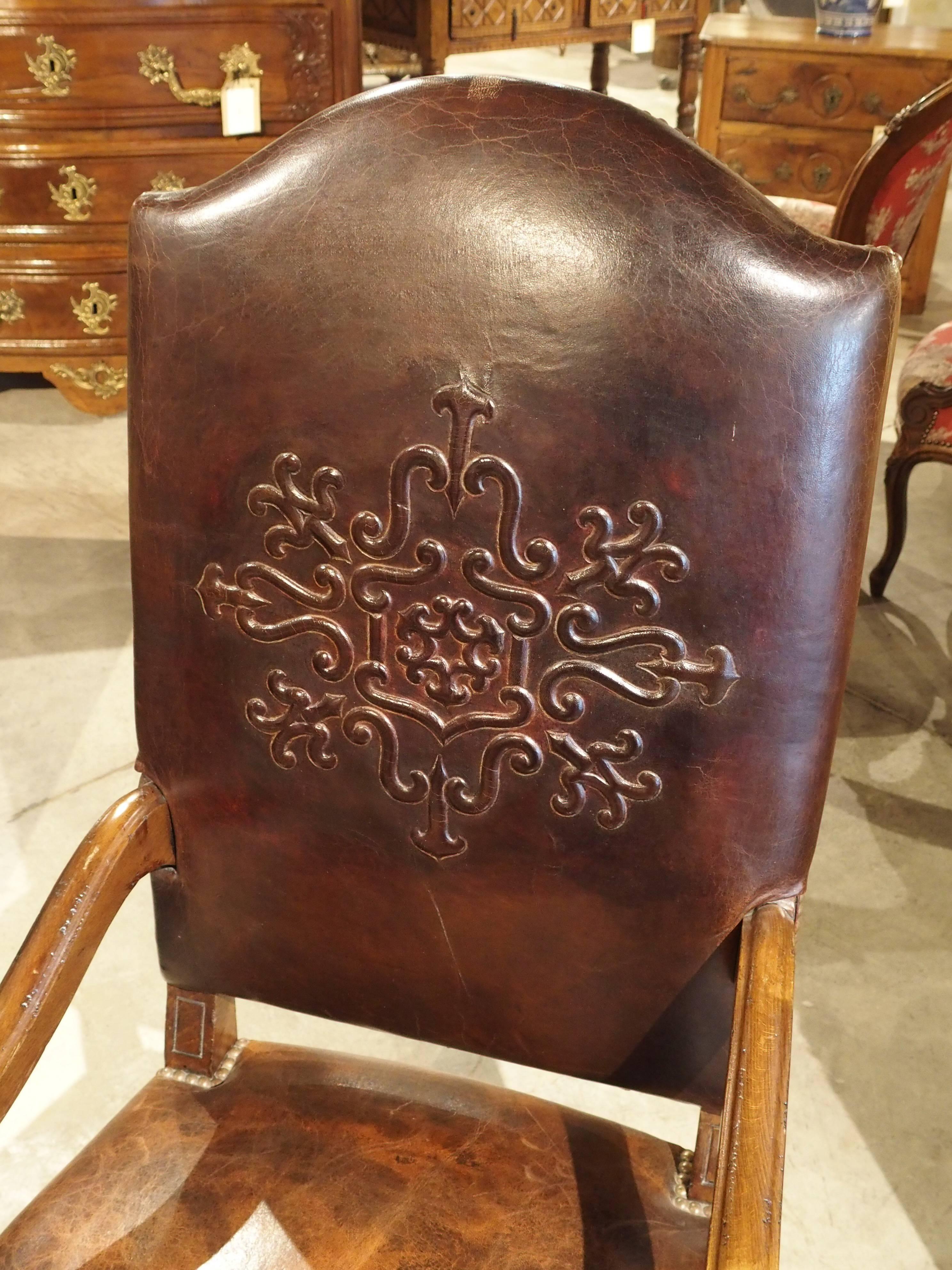 This is a handmade leather armchair from the South of France. The frame is constructed of French walnut and the leather is attached by hundreds of brass nail heads. This is a custom design made for our store and it is one of the last available. It