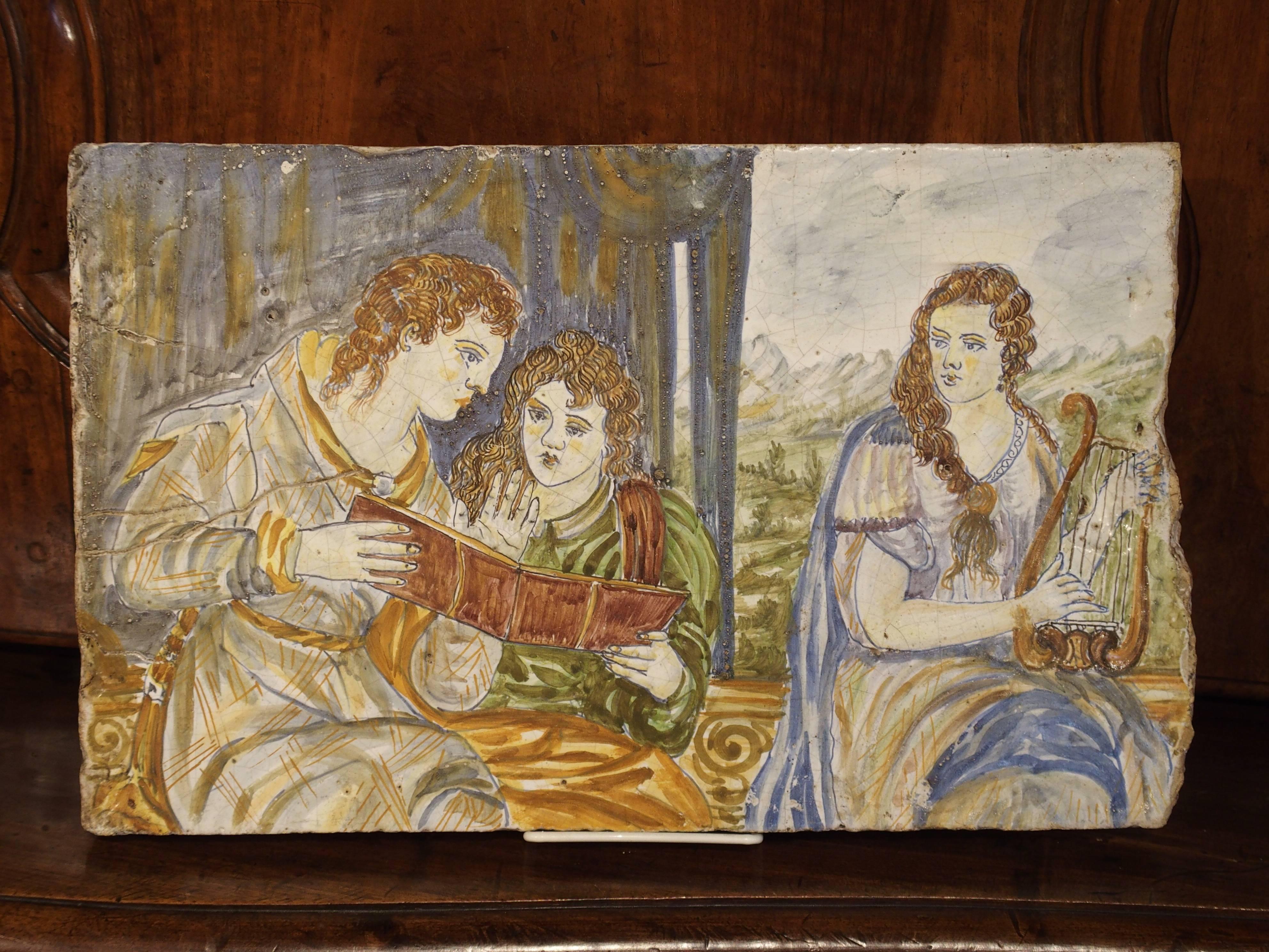 This impressive and very thick majolica or maiolica tile is from Italy and has hand-painted scenes known as istoriato wares (painted with stories). These scenes were painted on a white background in bright colors of blue, yellow, orange, green and