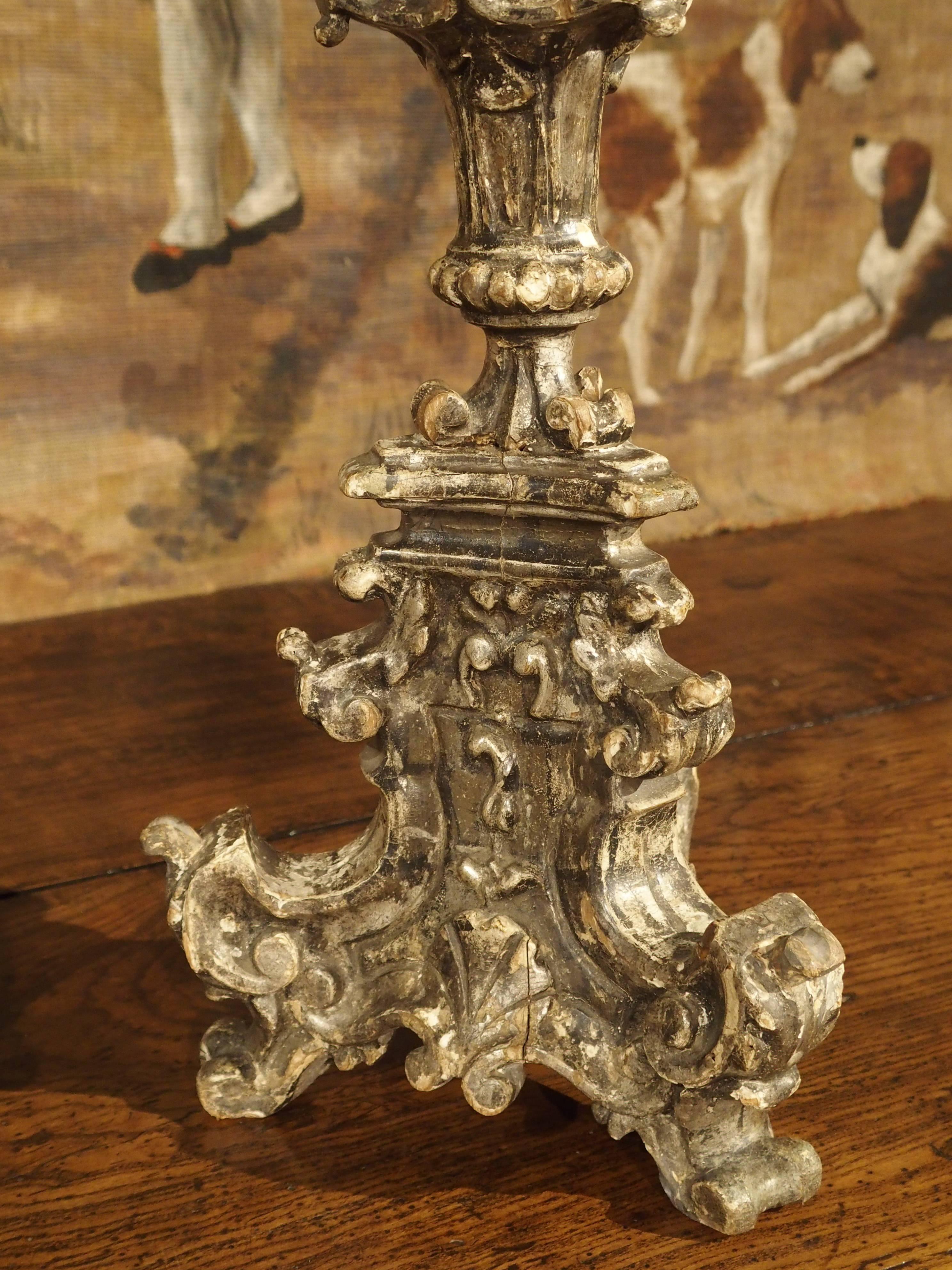 These Italian parcel silver leaf candlesticks are from the 1600’s, each with hand carved scrolls, elongated egg and dart, and acanthus leaf ornamented stems beneath a circular acanthus leaf decorated platform with a central pricket for the candle.