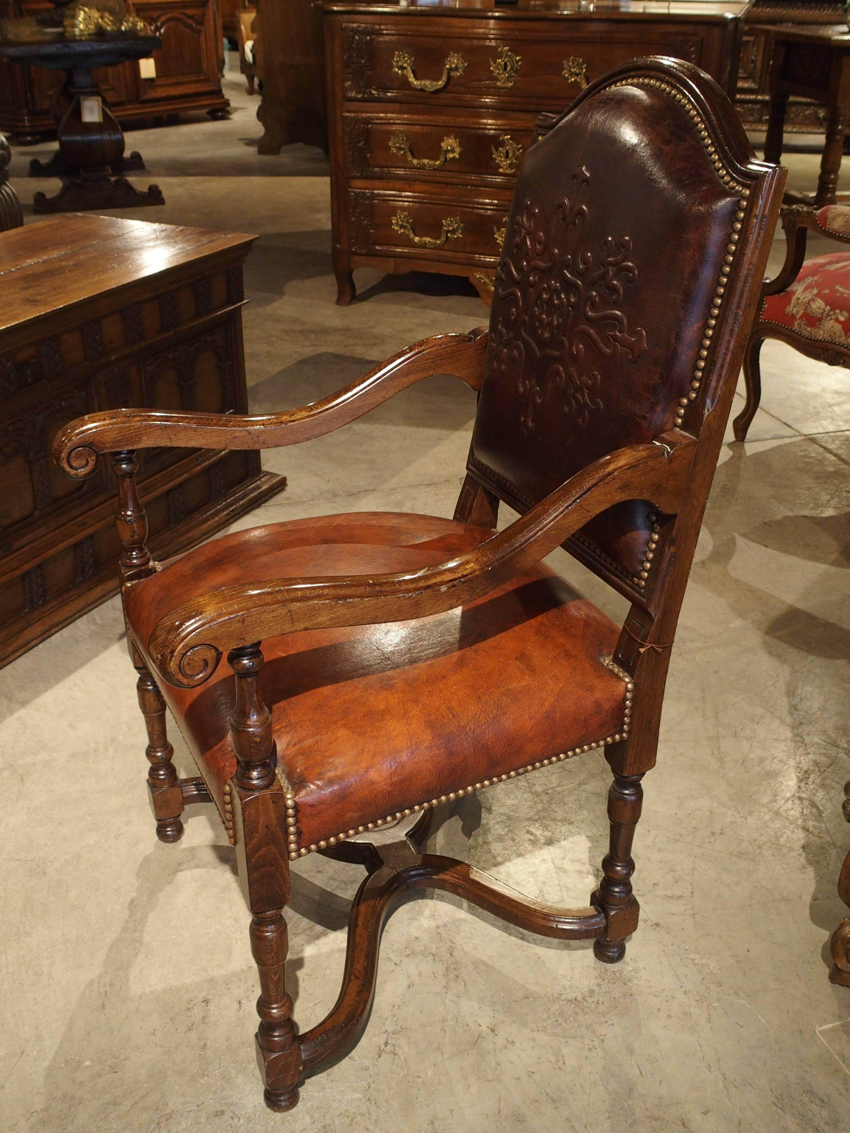 This is a handmade leather armchair from the South of France. The frame is constructed of French walnut and the leather is attached by hundreds of brass nailheads. This is a custom design made for our store, and it is one of the last available. It
