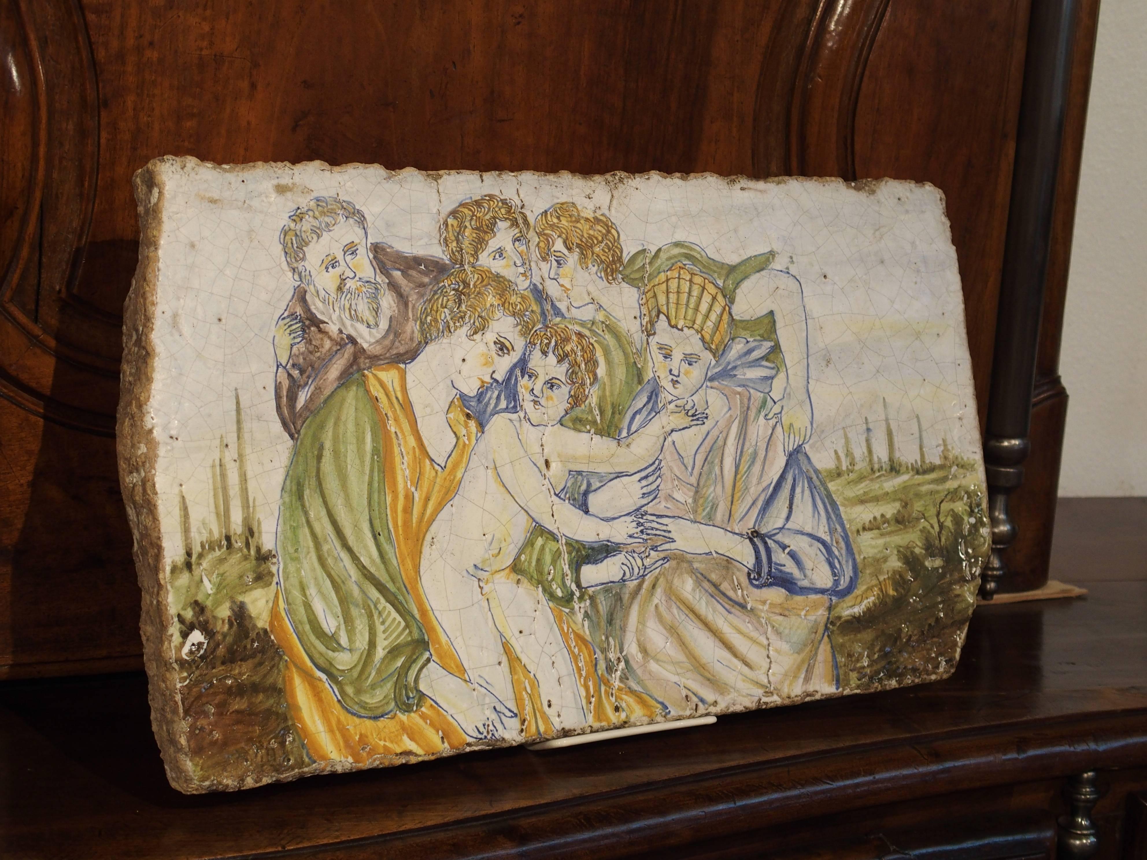 This impressive and very thick Majolica or Maiolica tile is from Italy and has hand-painted scenes known as istoriato wares (painted with stories). These scenes were painted on a white background in bright colors of blue, yellow, orange, green and