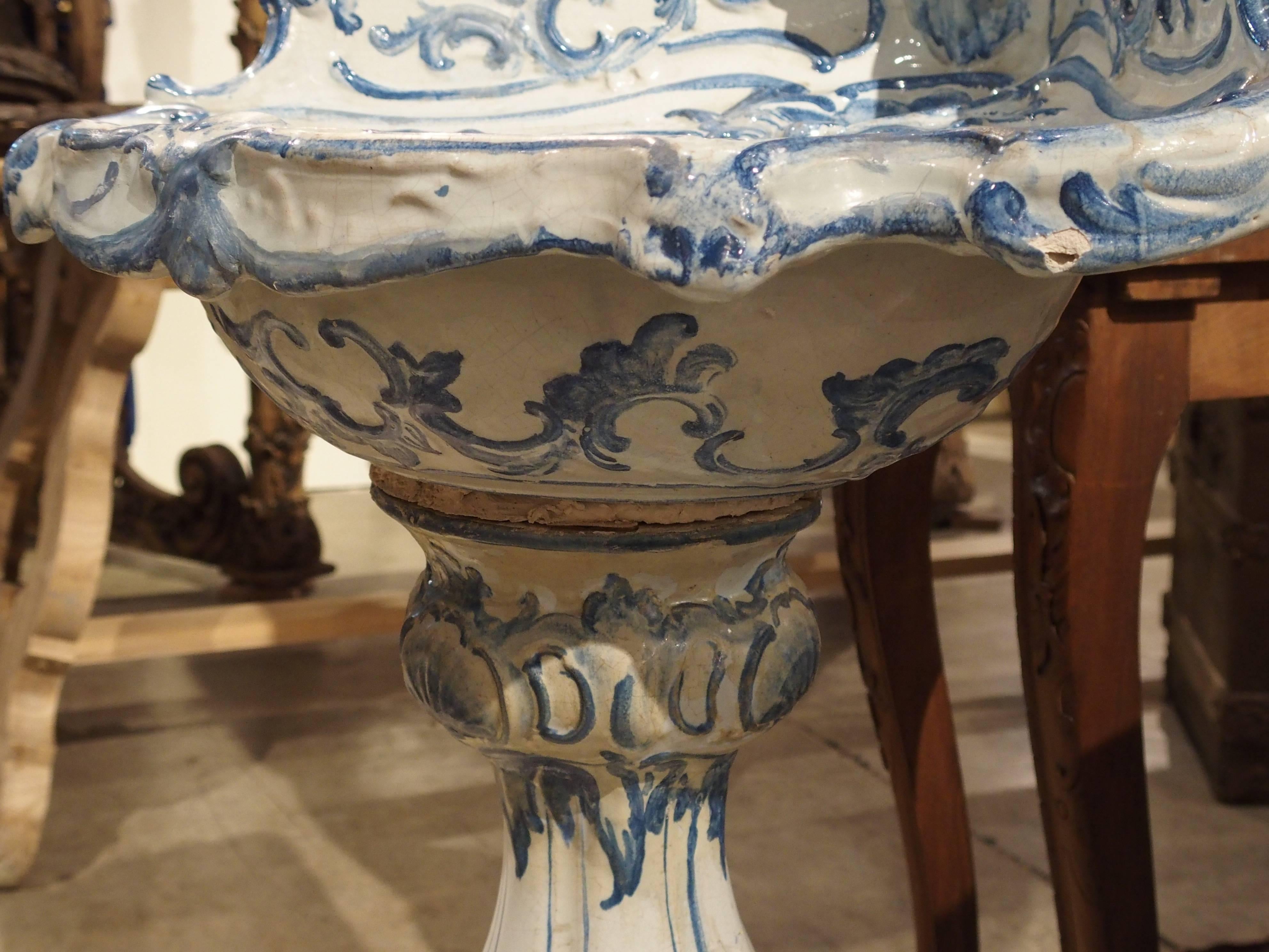 This stunning antique Italian, blue and white pedestal sink is from the late 1800s. The backsplash and sink rest upon a baluster with a tripod pedestal. The motifs are painted shells, leaves and stylized dolphins. In the sink there is a central