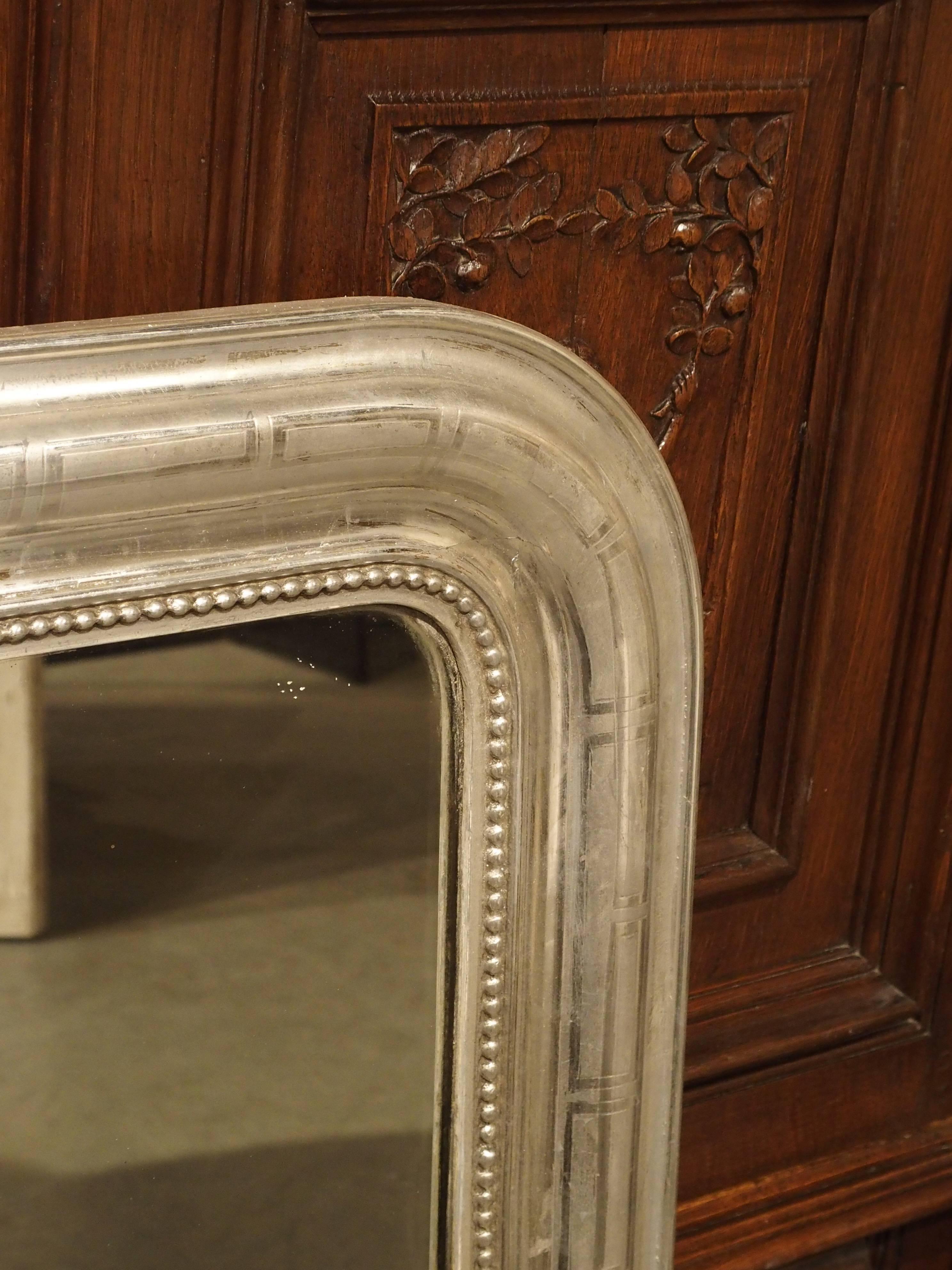 This versatile, antique French, silverleaf Louis Philippe mirror has matte and shiny areas highlighting a simple geometric pattern on molding. There is linear beading on the inside molding, and the silvered glass has the desirable losses to it in